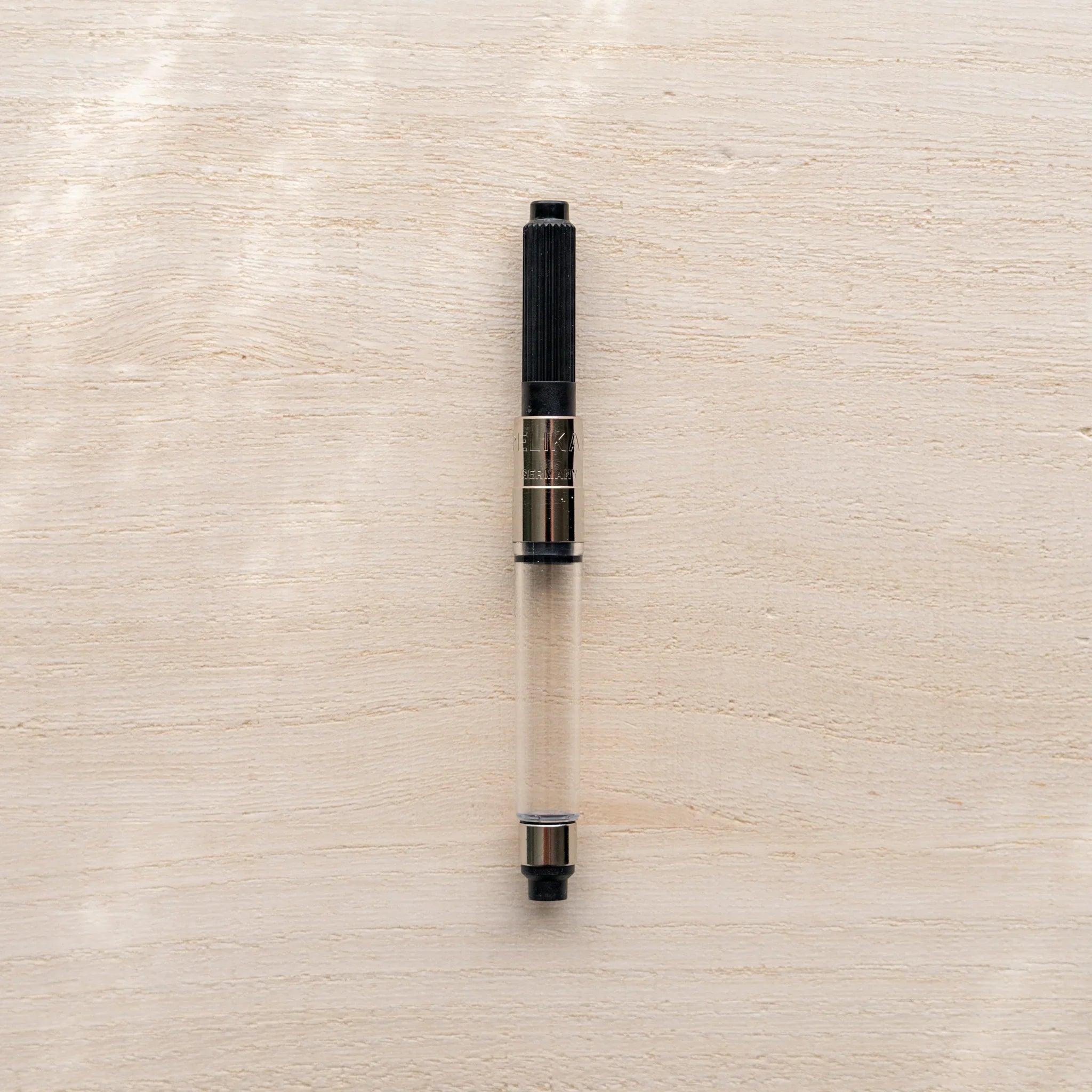 Pelikan piston converter compatible with Yamanaka Japanese fountain pens shown alone on a wood surface.