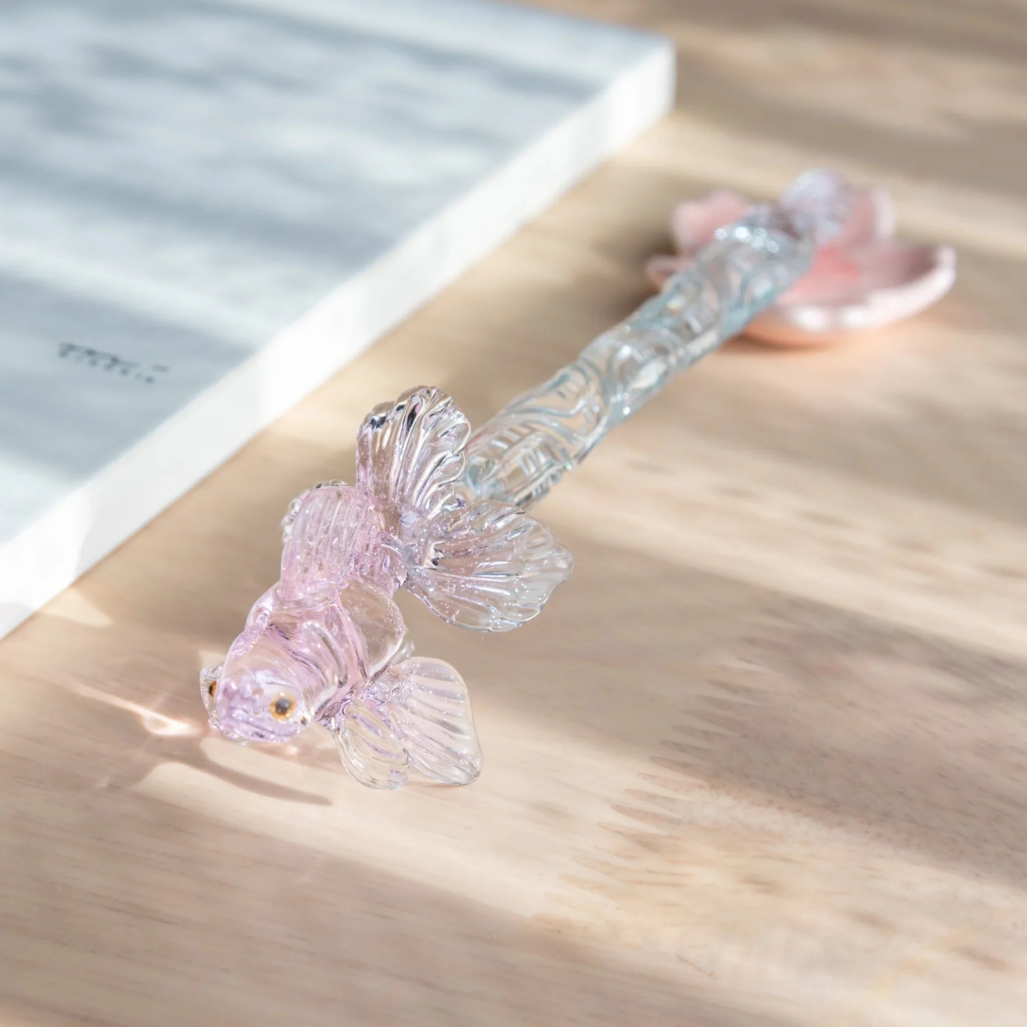 Pink Goldfish glass dip pen with twisted metal nib displayed at angle showing pale pink translucent barrel shine