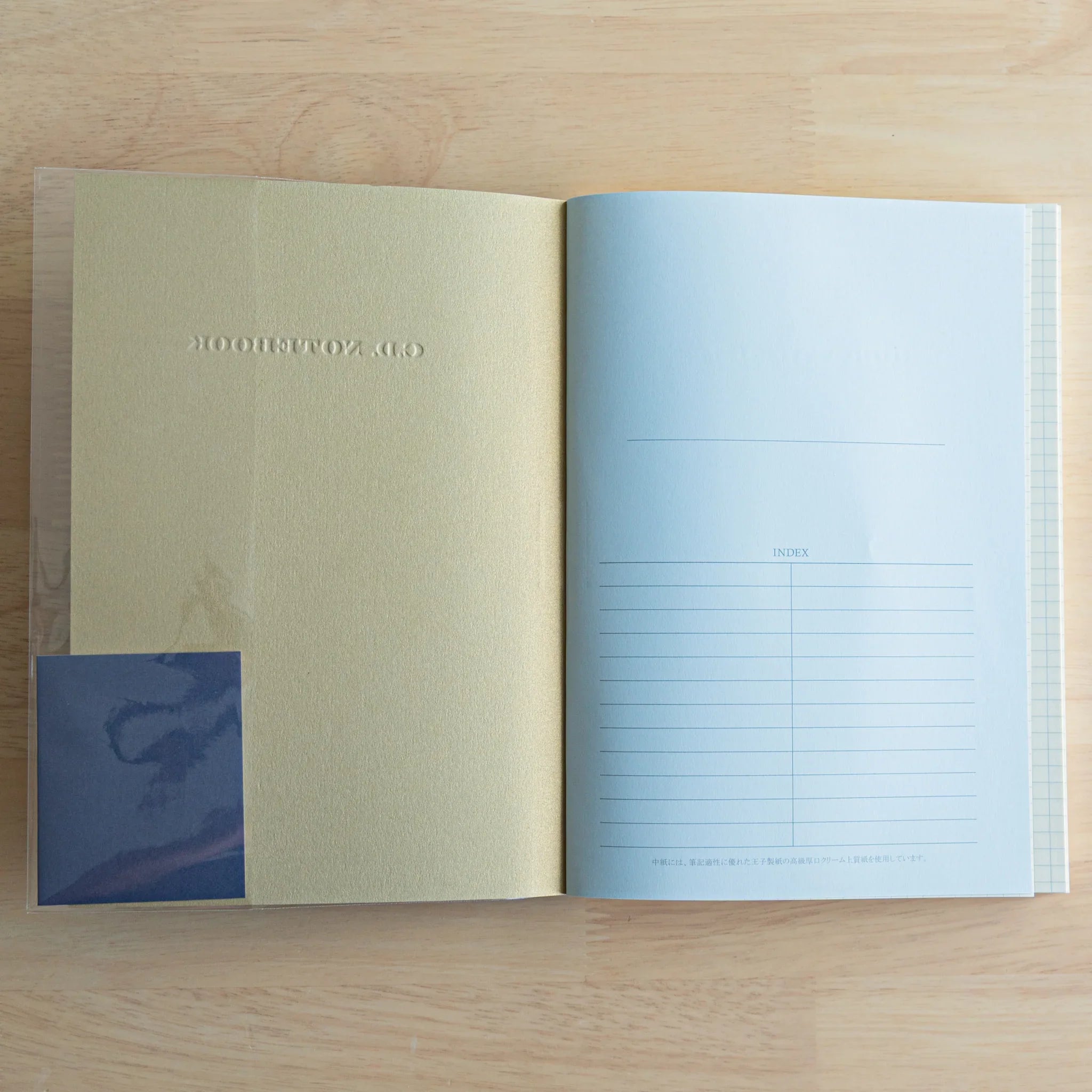 Apica Premium CD A5 cream-colored notebook flat lay showing cover and opened interior with light blue ruled pages