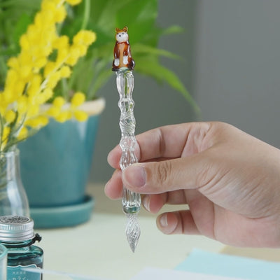 Japanese Shiba Inu glass dip pen with textured ribbed glass barrel and ceramic dog figurine, artistic composition display