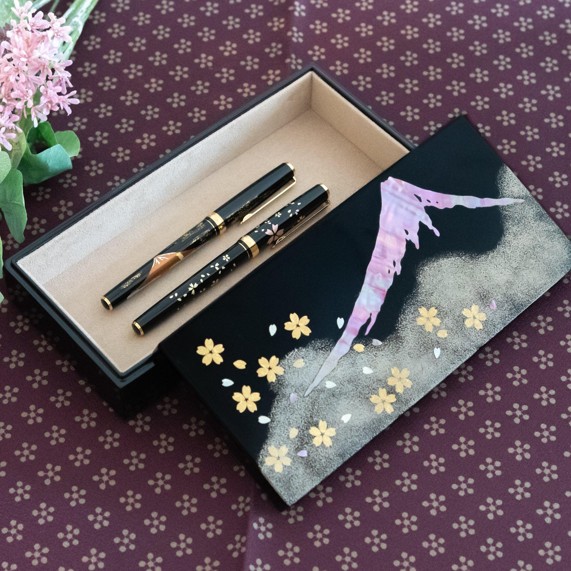 Black lacquer Japanese pen box open with raden Mt. Fuji and gold leaf sakura on lid, holding two fountain pens