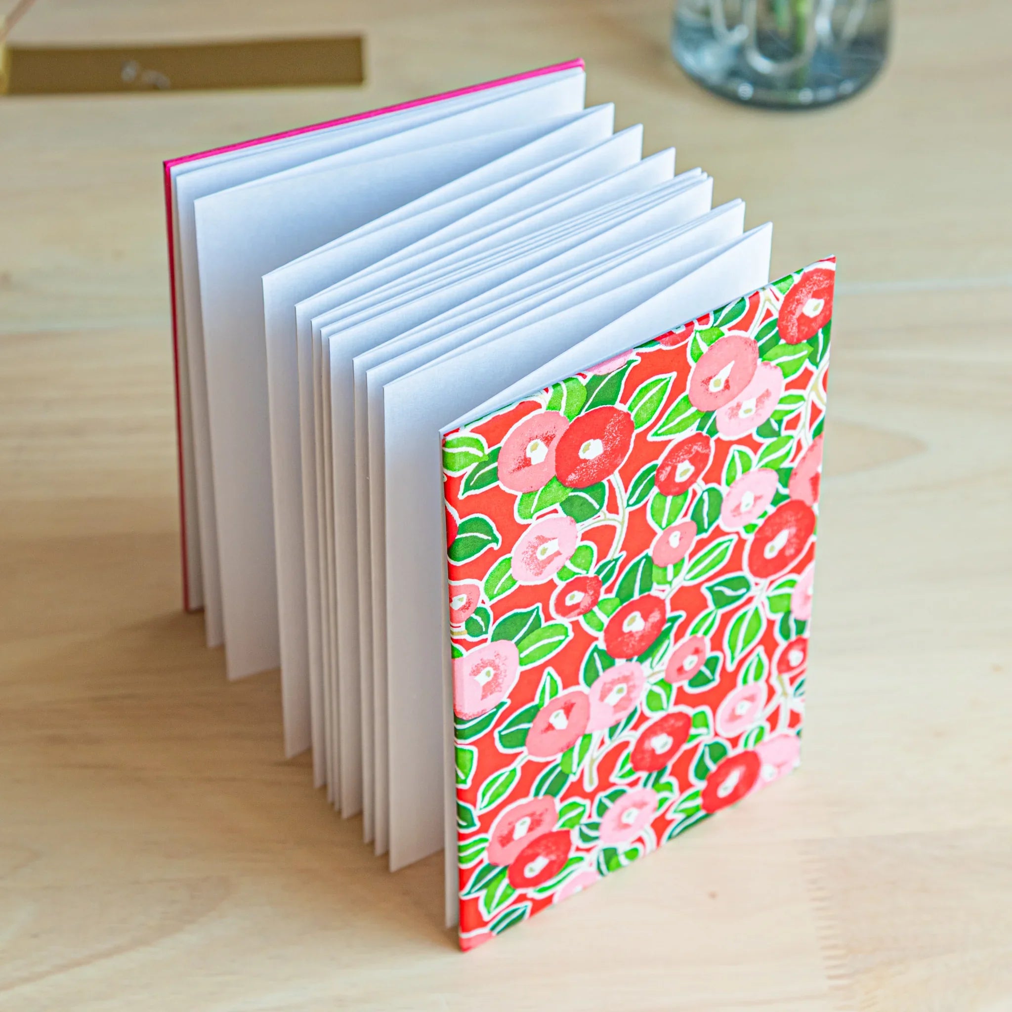 Red Camellia washi goshuincho stamp book standing upright with accordion fold pages visible and hot pink binding spine
