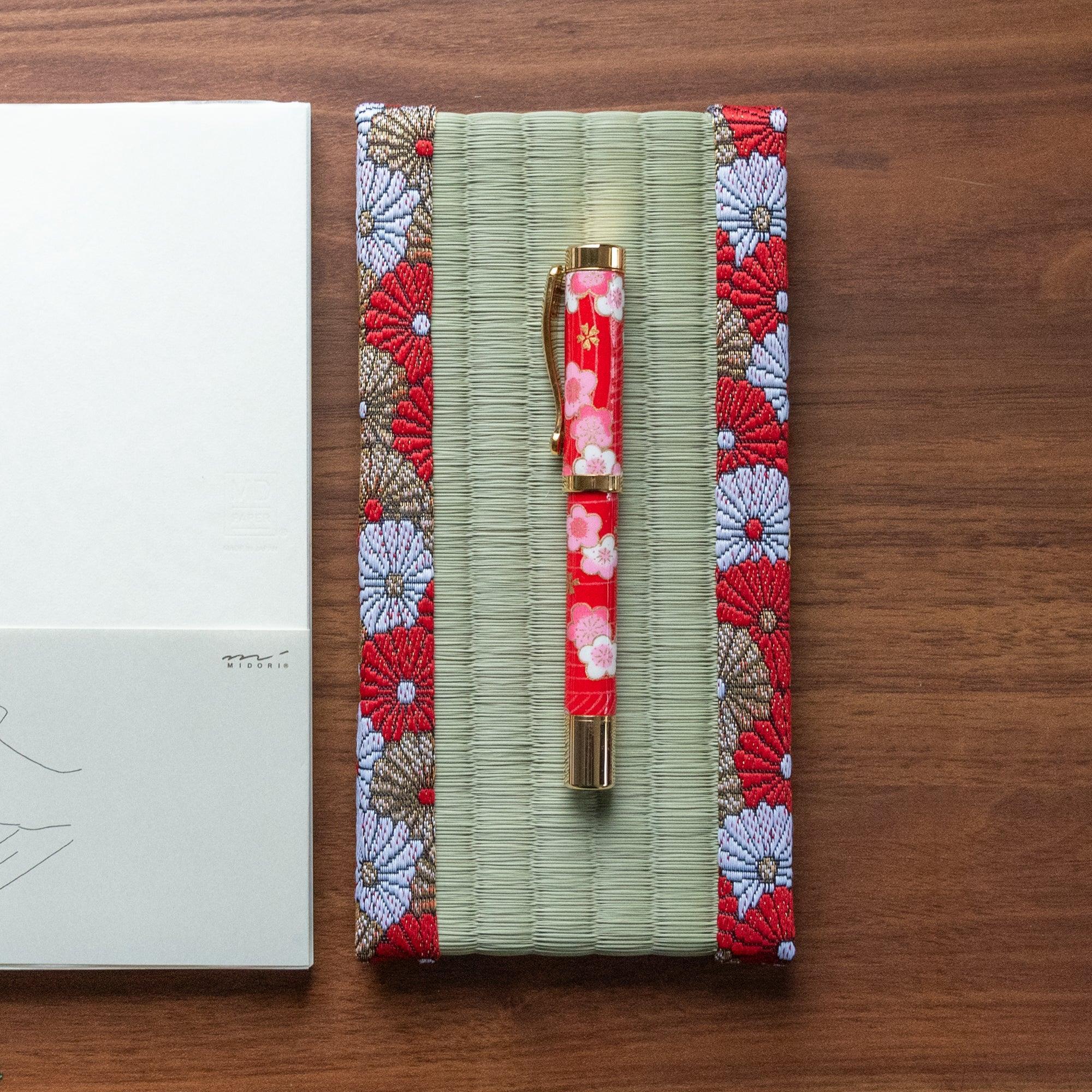 Japanese tatami pen tray with chrysanthemum brocade border holding a red floral fountain pen on walnut wood