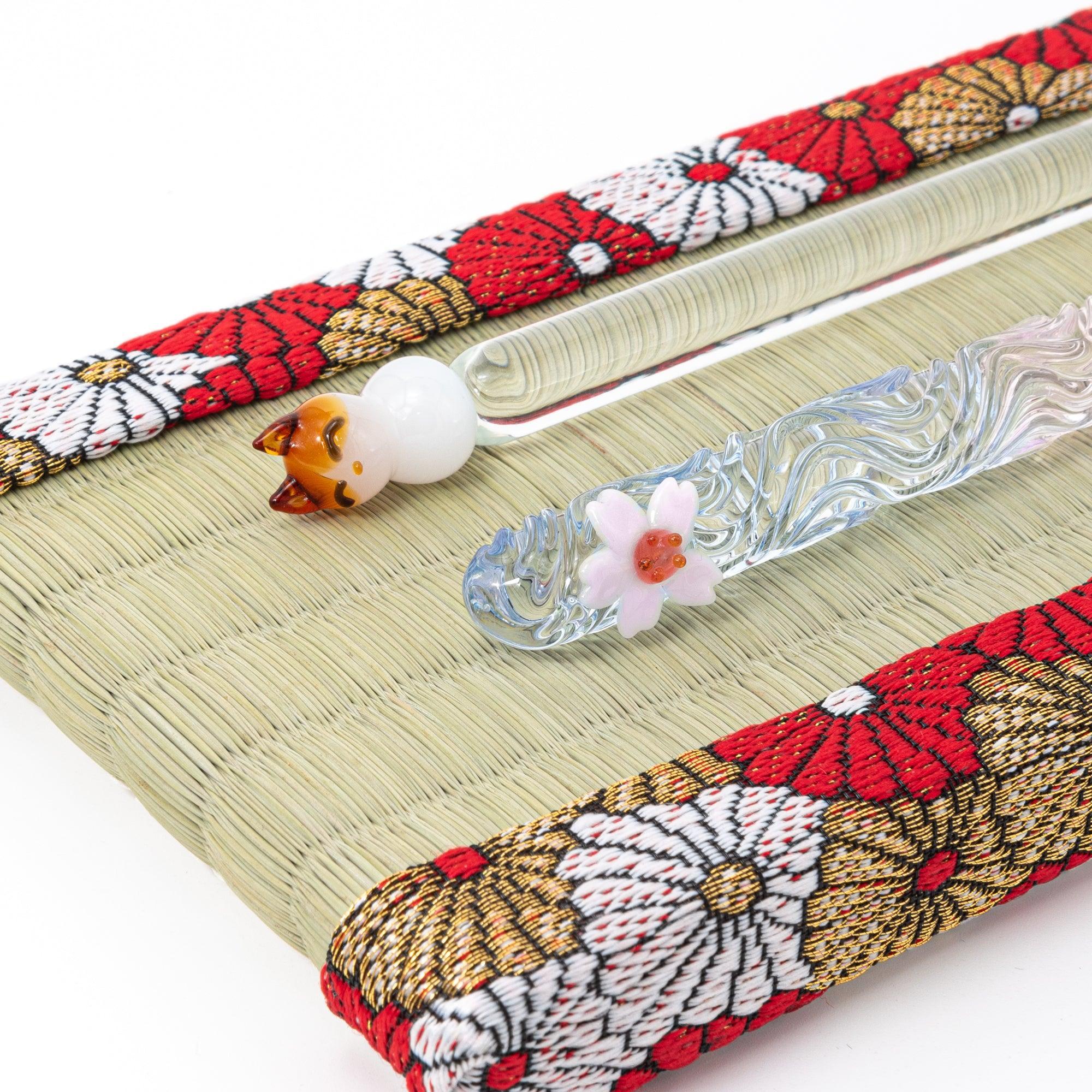 Close-up of Japanese tatami pen tray holding cat figurine glass dip pen and blue wave glass dip pen on white background