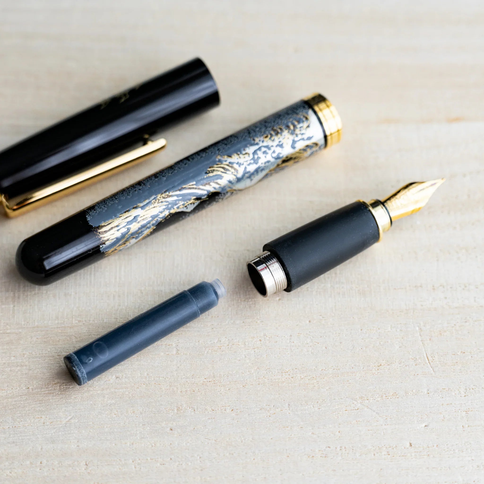 Black Yamanaka fountain pen taken apart showing barrel, cap, gold nib section and a black S.T. Dupont ink cartridge