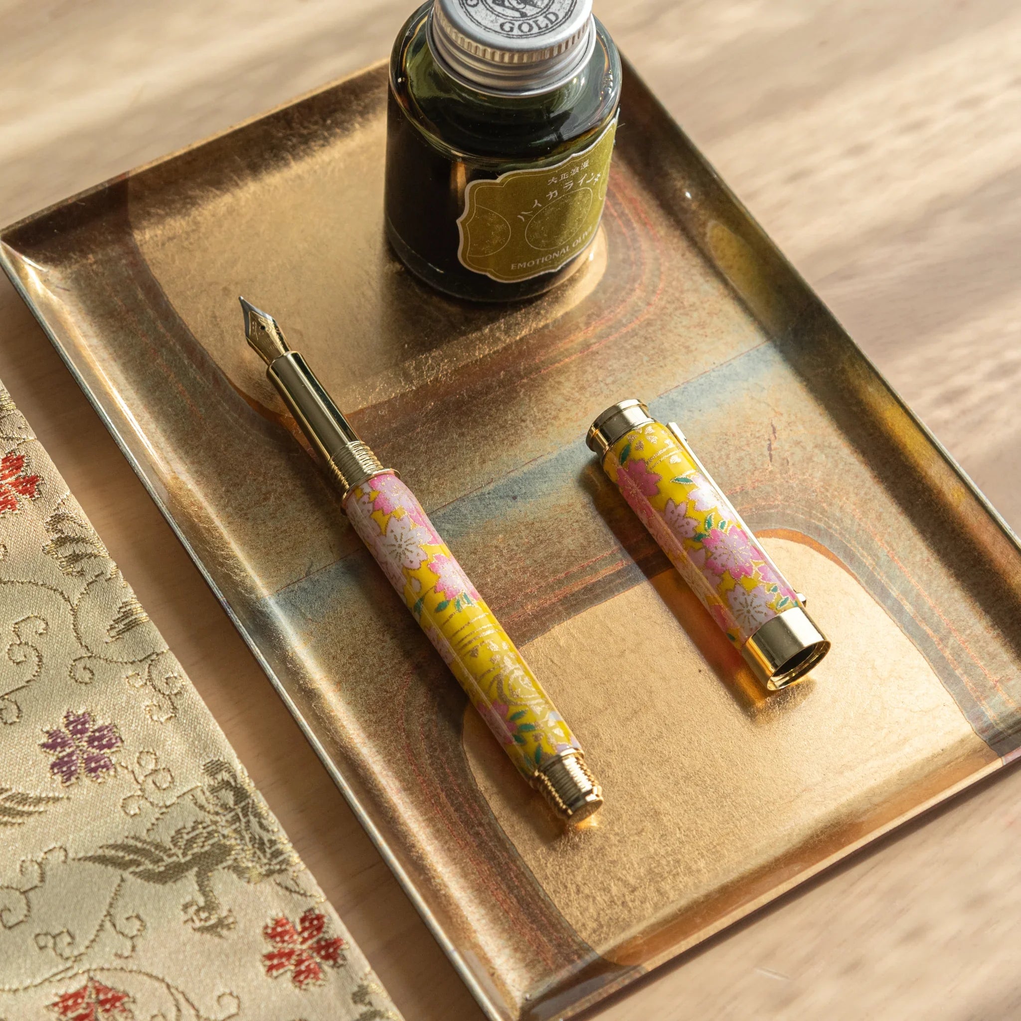 Sakura and Canola Mino washi fountain pen displayed on botanical cream fabric with yellow flower design with nib
