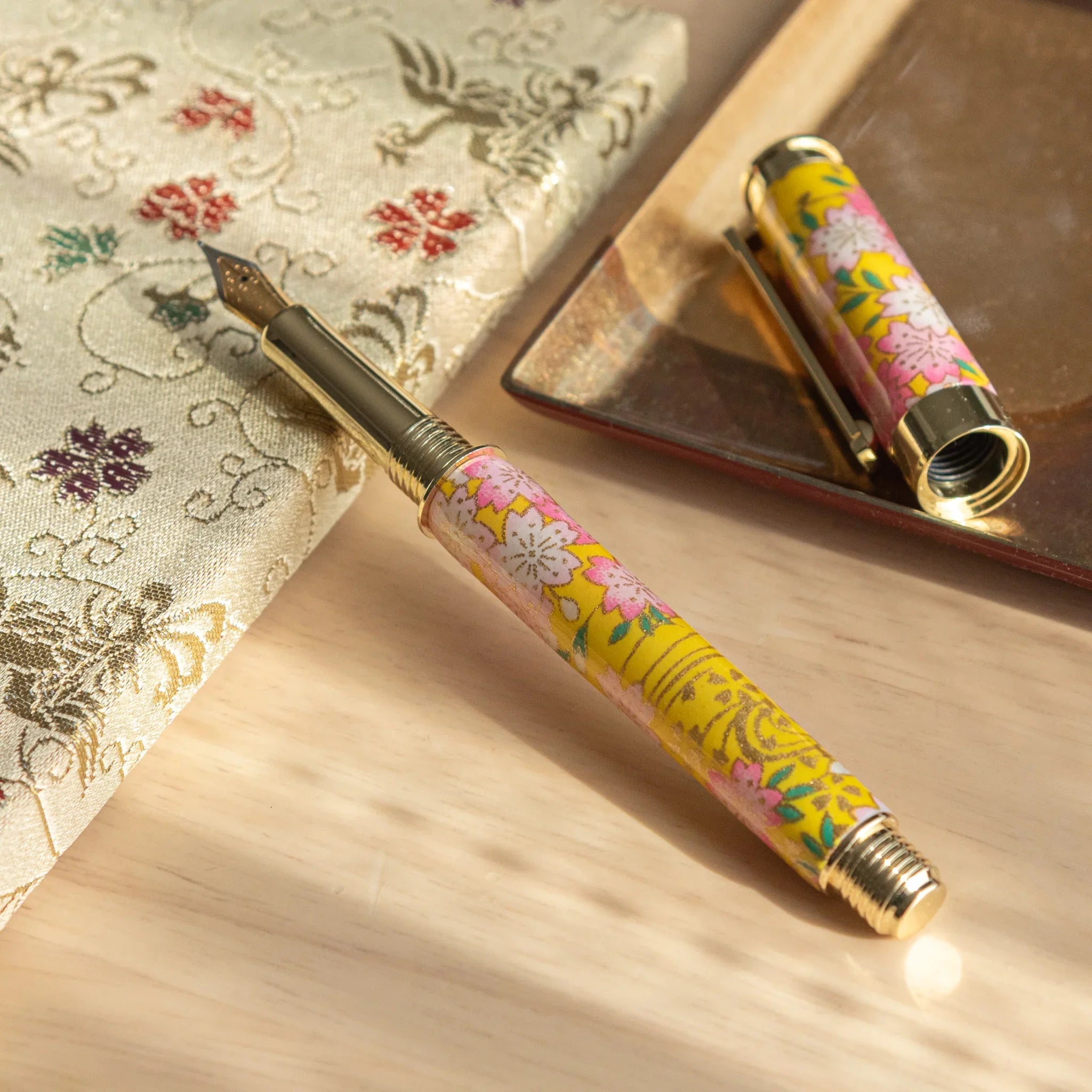 Japanese fountain pen with light colored Mino washi featuring yellow rape flowers and pink cherry blossoms angle