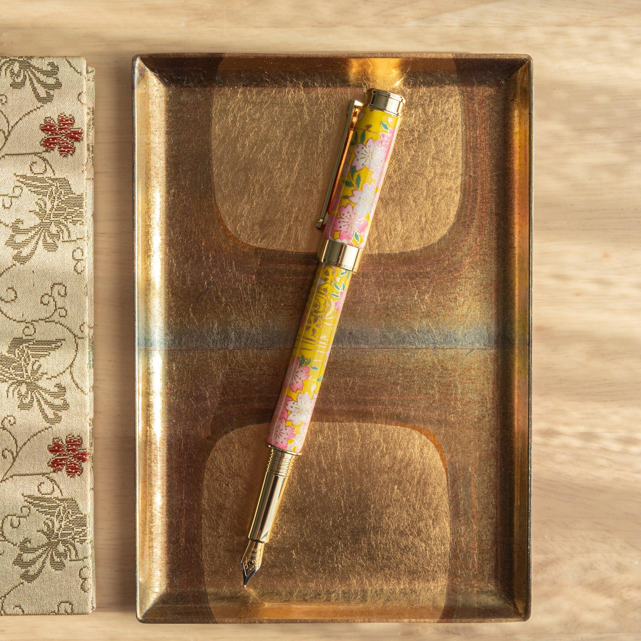 Uncapped Sakura and Canola Mino Washi fountain pen with pink and yellow floral Mino washi paper wrapping with nib