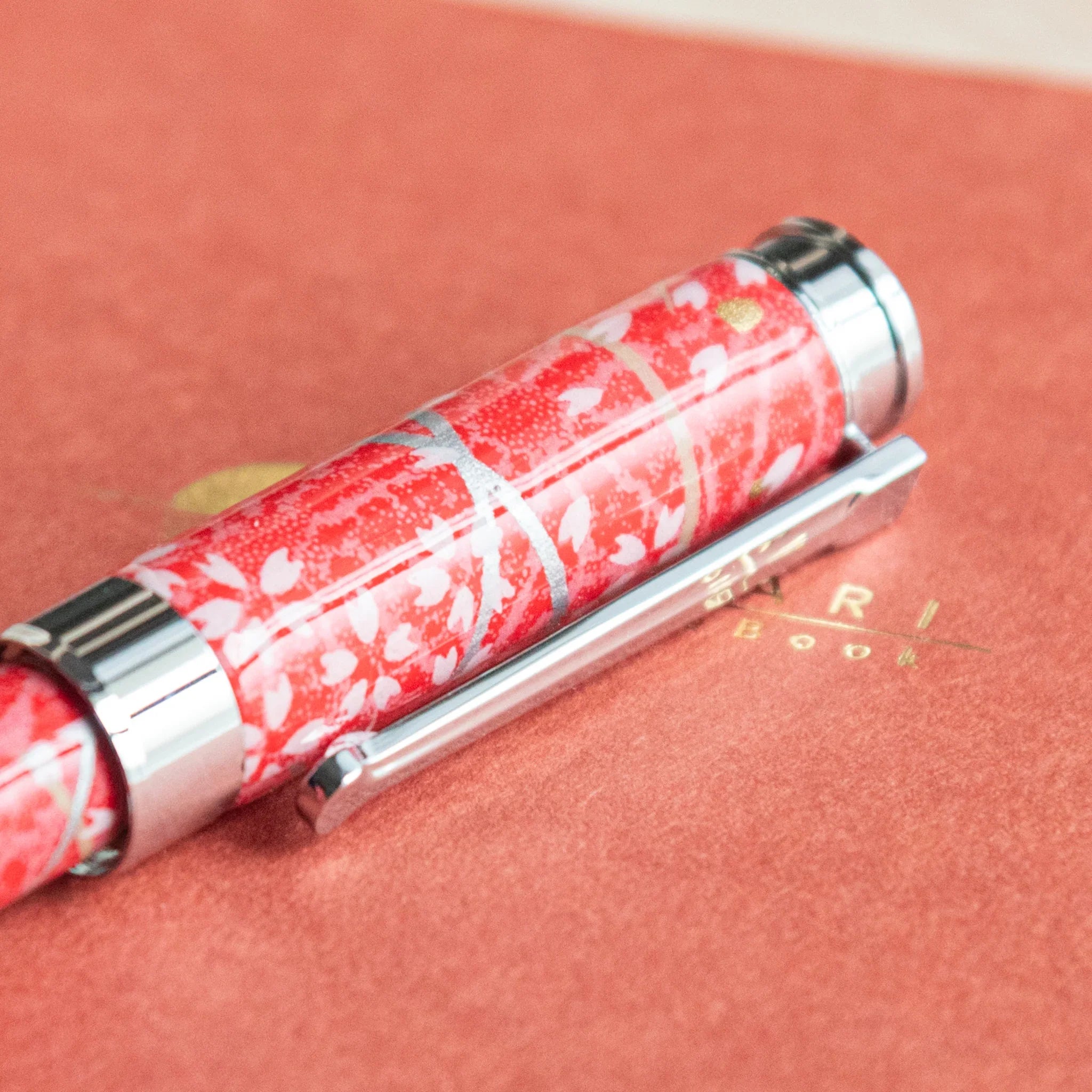 Sakura and Hemp Leaves Mino Washi fountain pen positioned on red background with white leafy pattern angled view