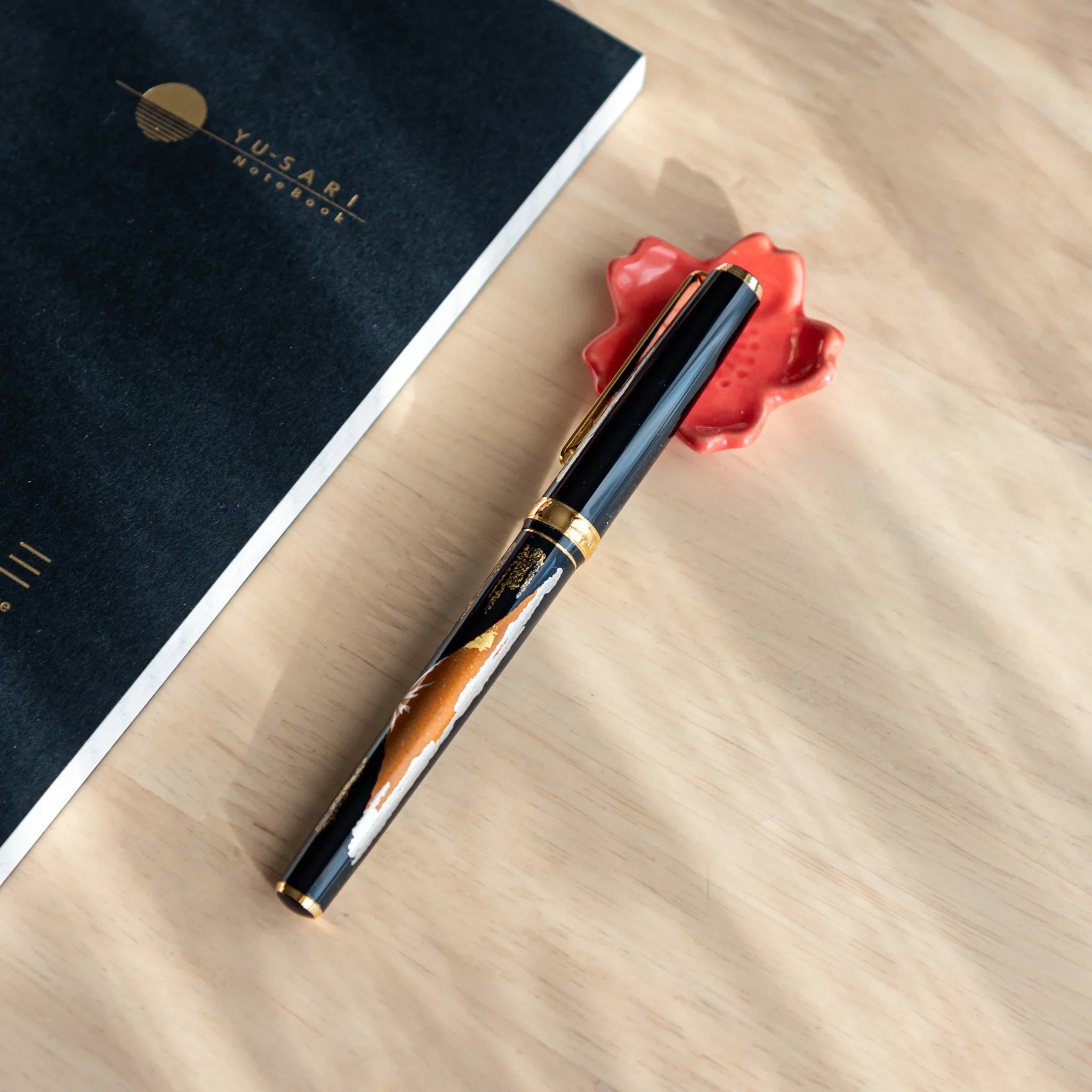 Light pink ceramic sakura flower pen rest showing fine textured petal details with smooth glazed finish close shot
