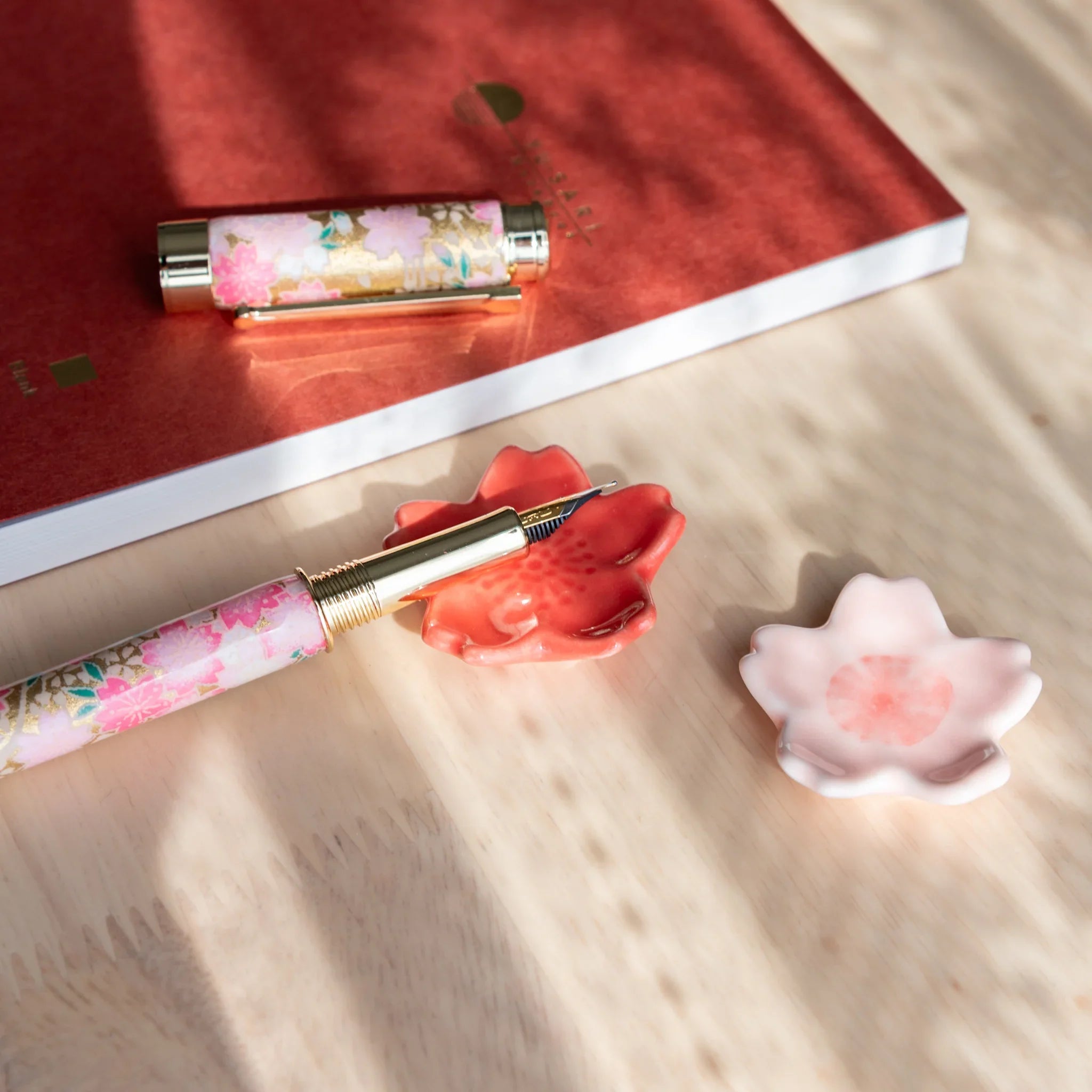 Light pink sakura ceramic pen rest with detailed petal relief design and glossy smooth finish overall close shot