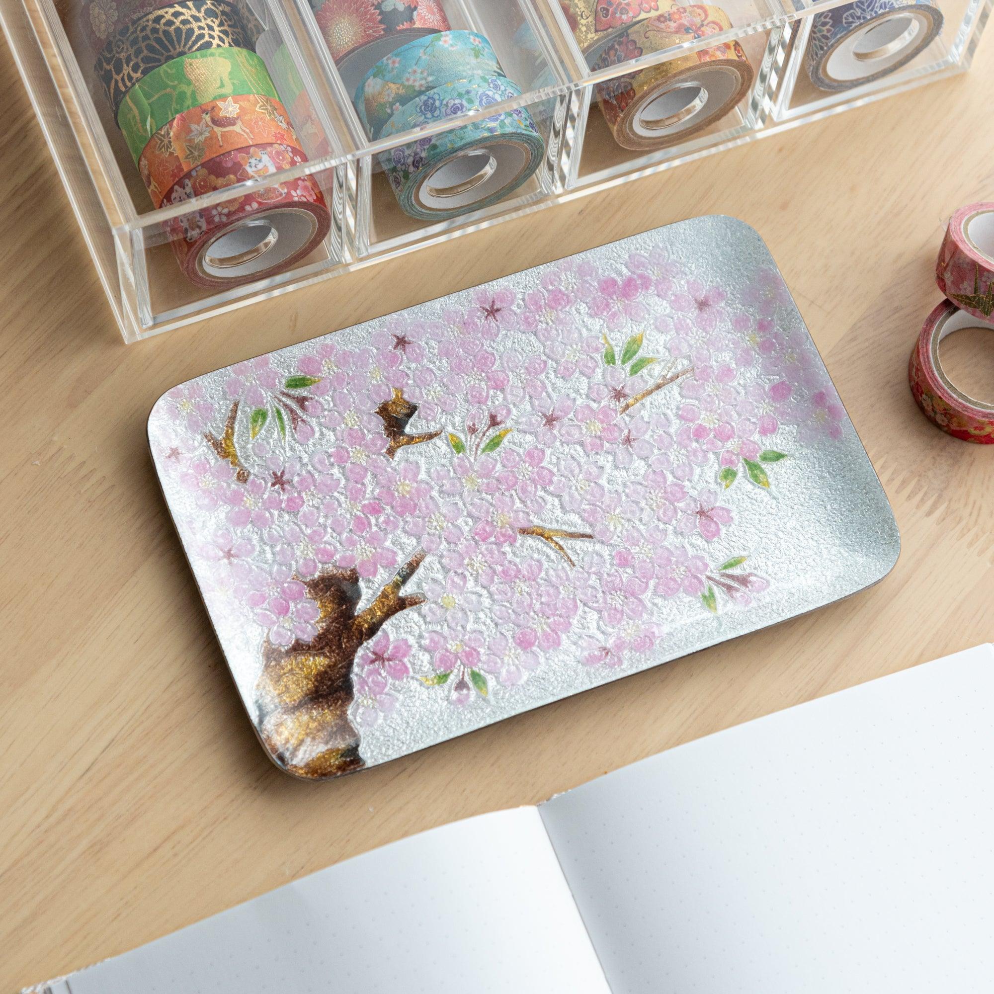 Japanese shippo ware pen tray with pink sakura tree design on silver, on wood desk with washi tape organizer