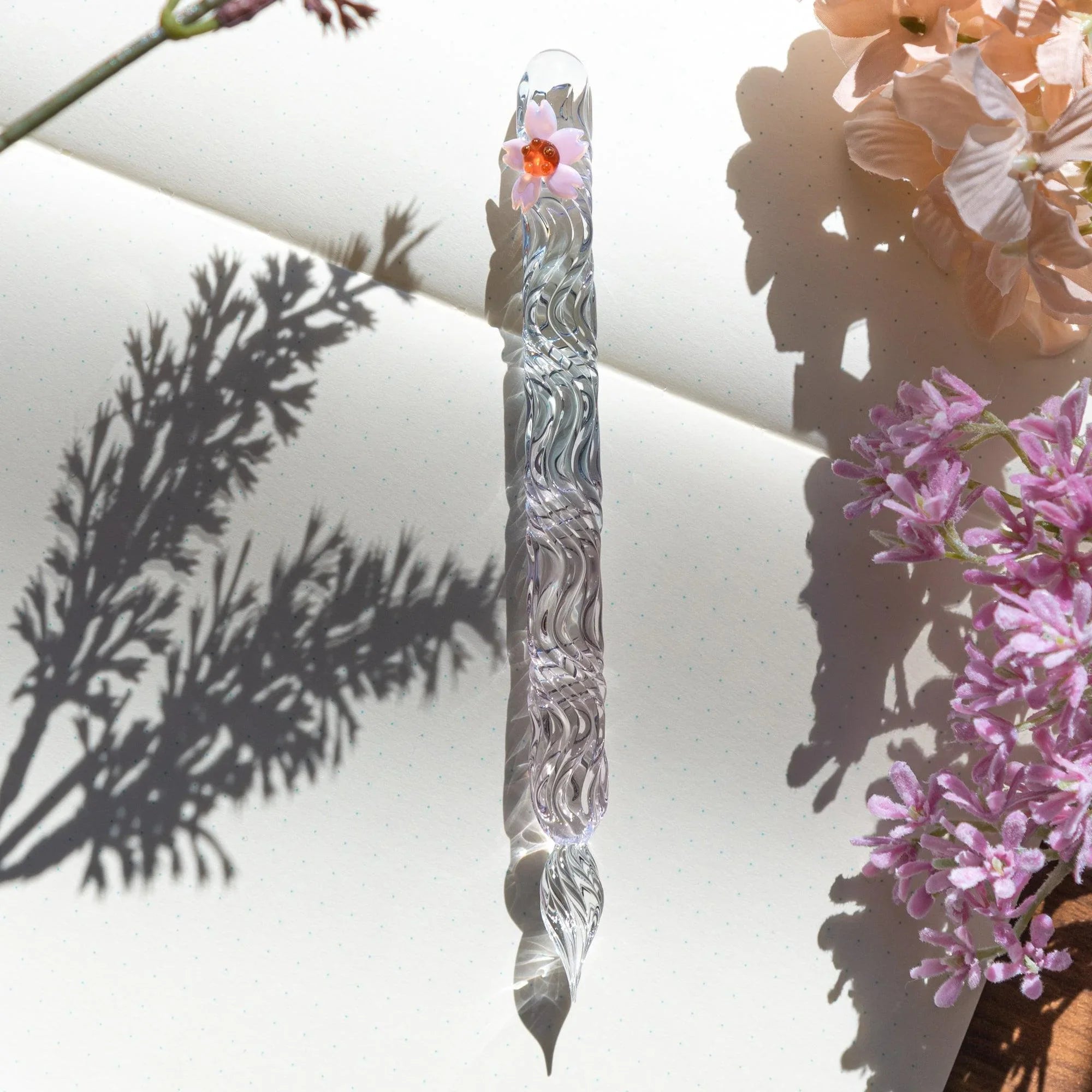 Sakura glass dip pen with pale pink tones and hand-twisted nib showcasing Japanese artisanal craftsmanship shine