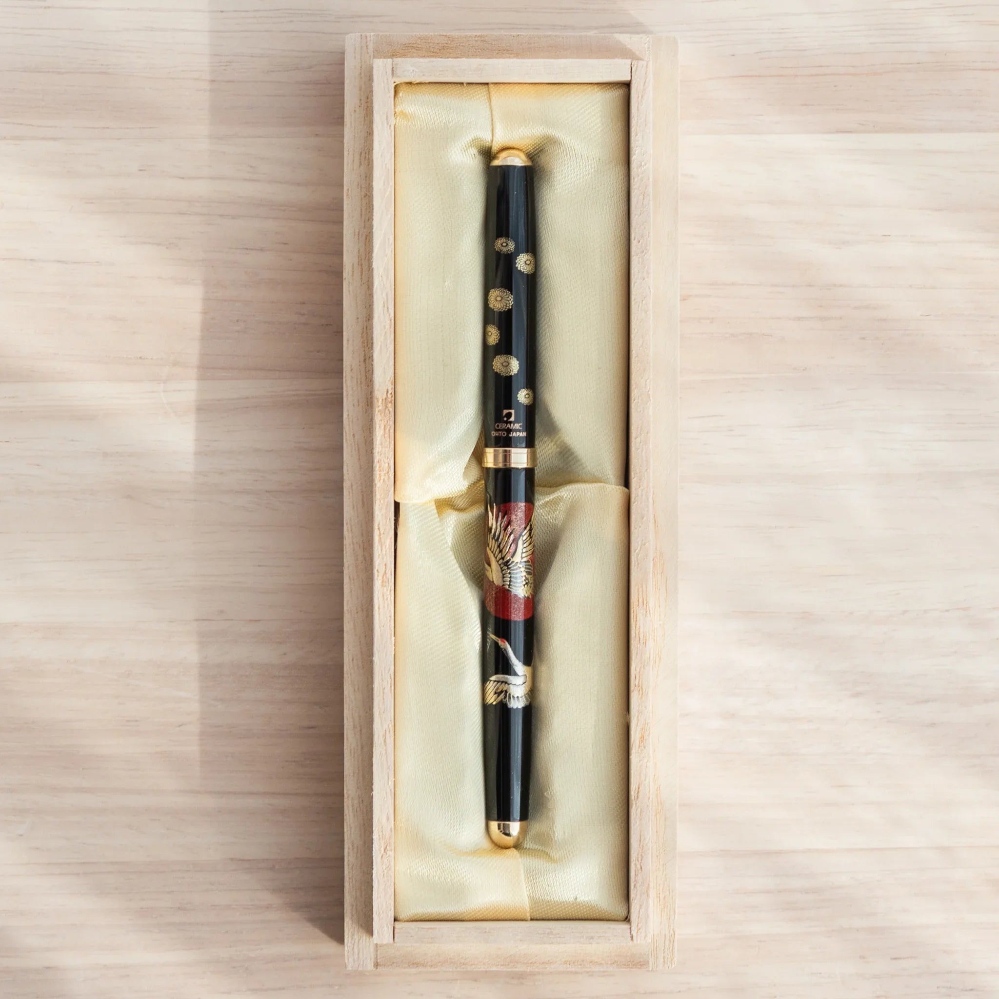 Black lacquer Japanese ballpoint pen with crane and sunrise pattern in open natural wood gift box with cream satin lining