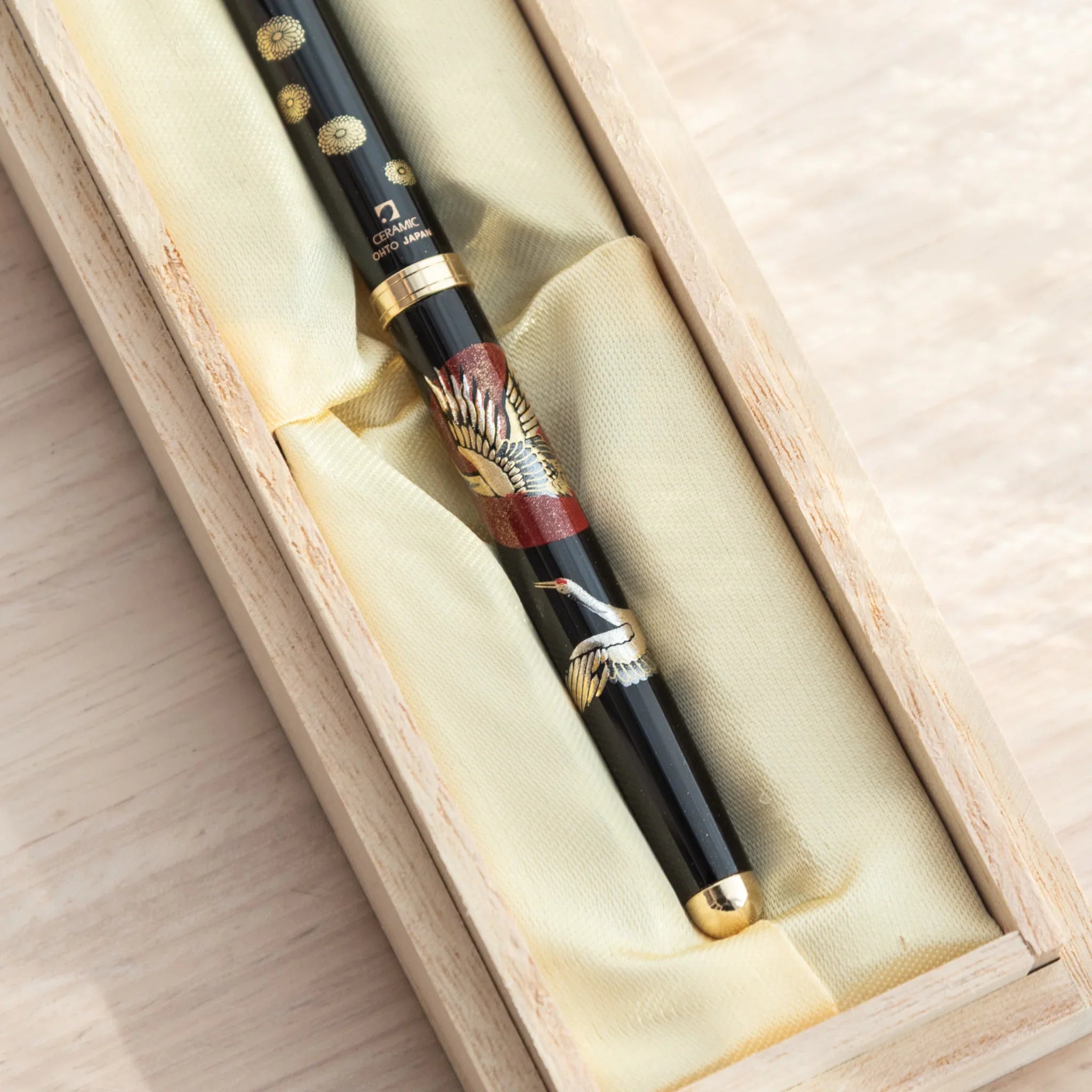 Japanese ballpoint pen in open natural wood gift box showing crane and red sun barrel pattern and Ceramic Ohto Japan label