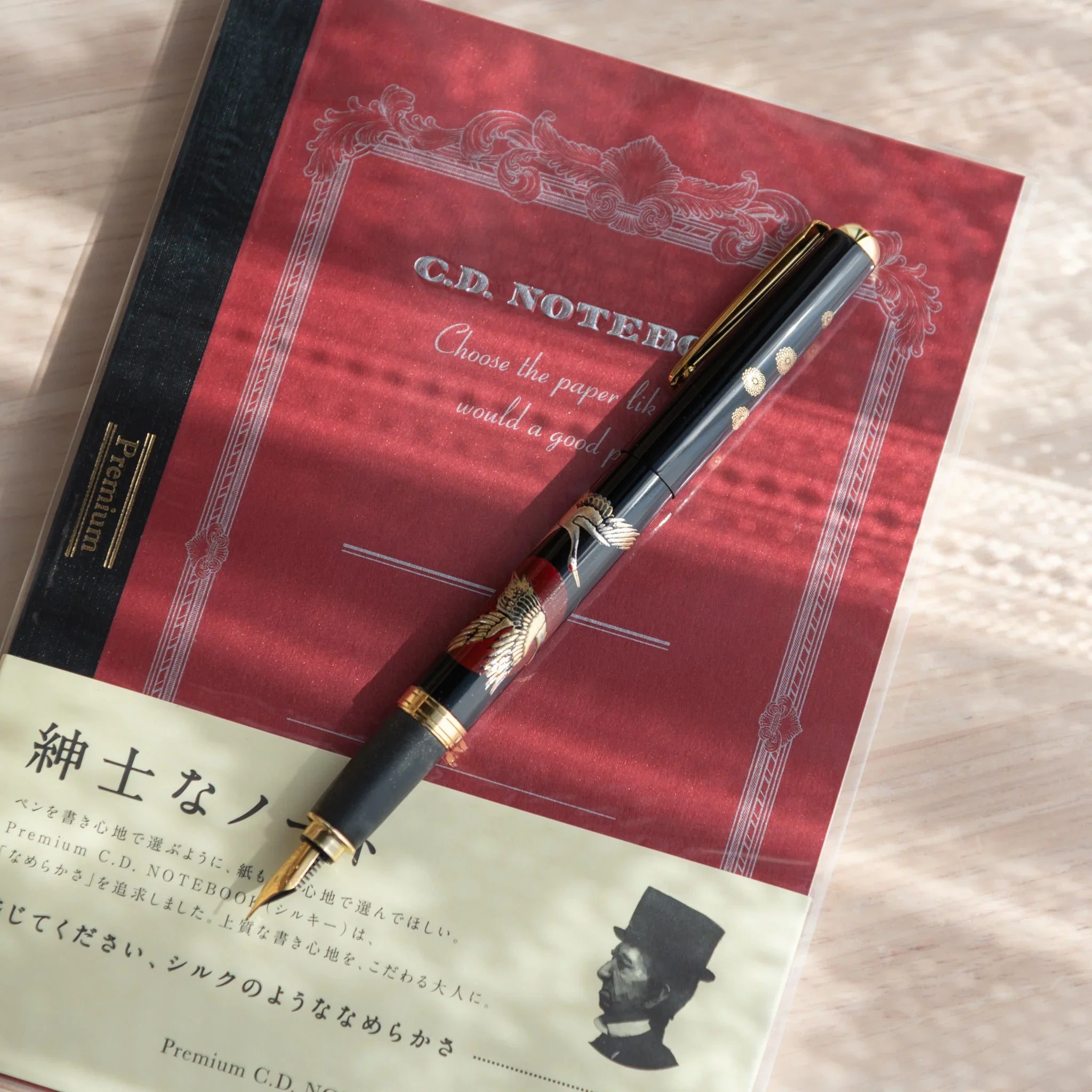 Yamanaka lacquer fountain pen displays hand-painted sunrise cranes in gold and warm lacquer for writing