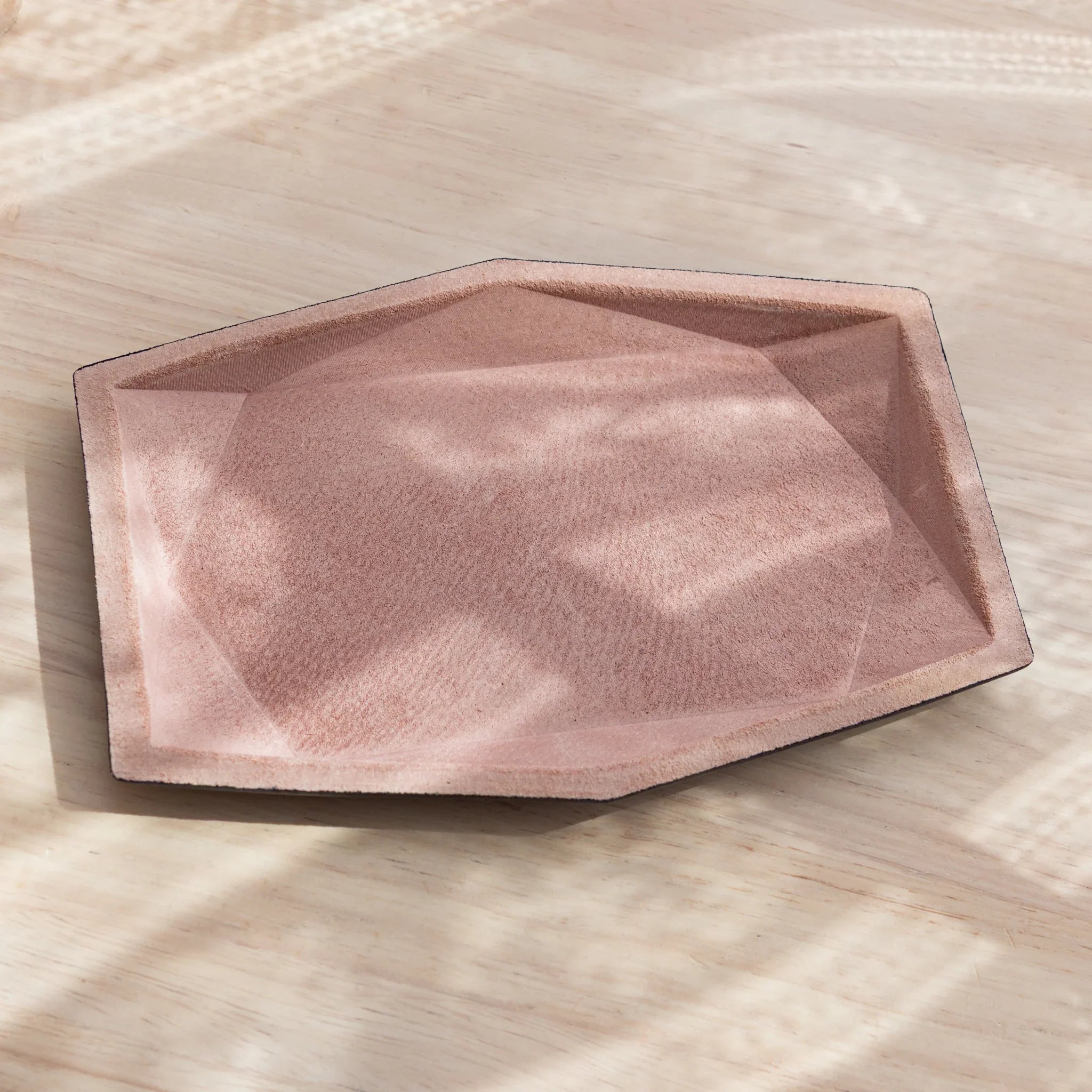 Pink suede wide hexagonal pen tray empty from an angle showing geometric faceted interior walls and black leather rim