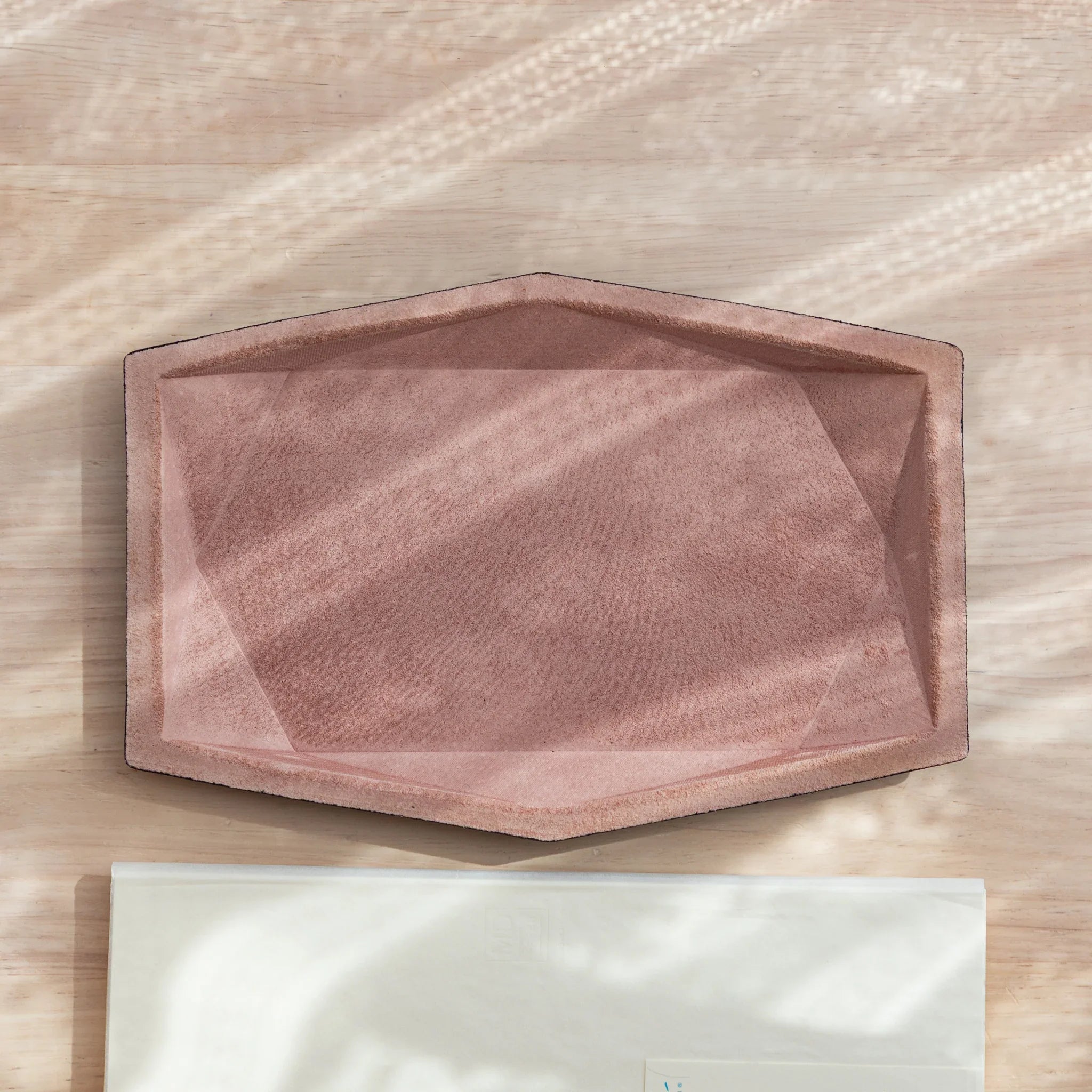 Pink suede wide hexagonal pen tray overhead empty showing geometric hex shape and faceted interior walls on white surface