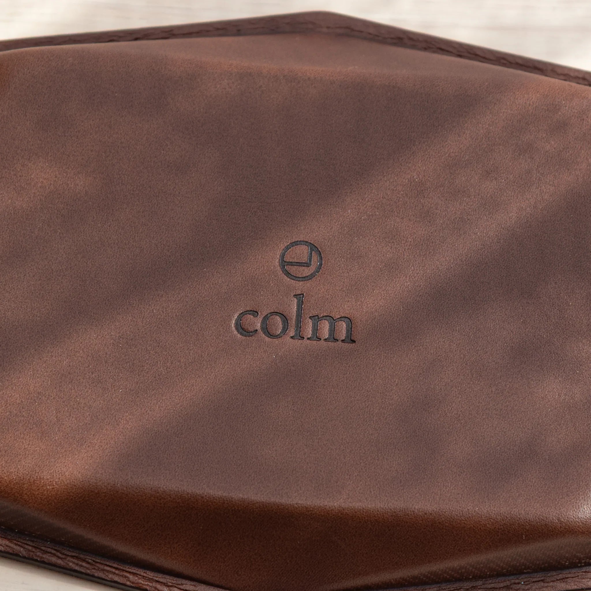 Close-up of brown leather base of wide hexagonal pen tray with embossed colm logo and geometric hex corner detail
