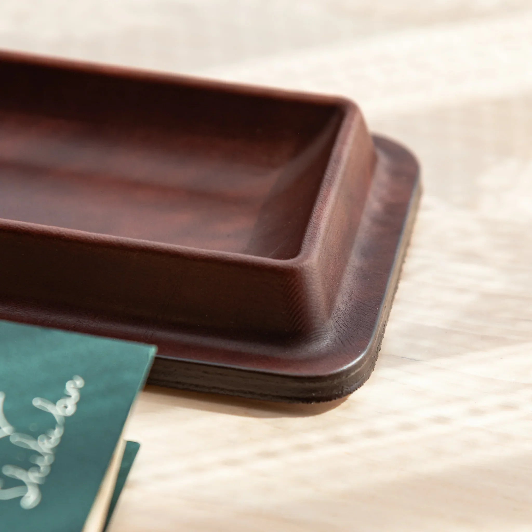 Burgundy leather pen tray corner detail showing leather grain pattern and smooth curved edge clearly