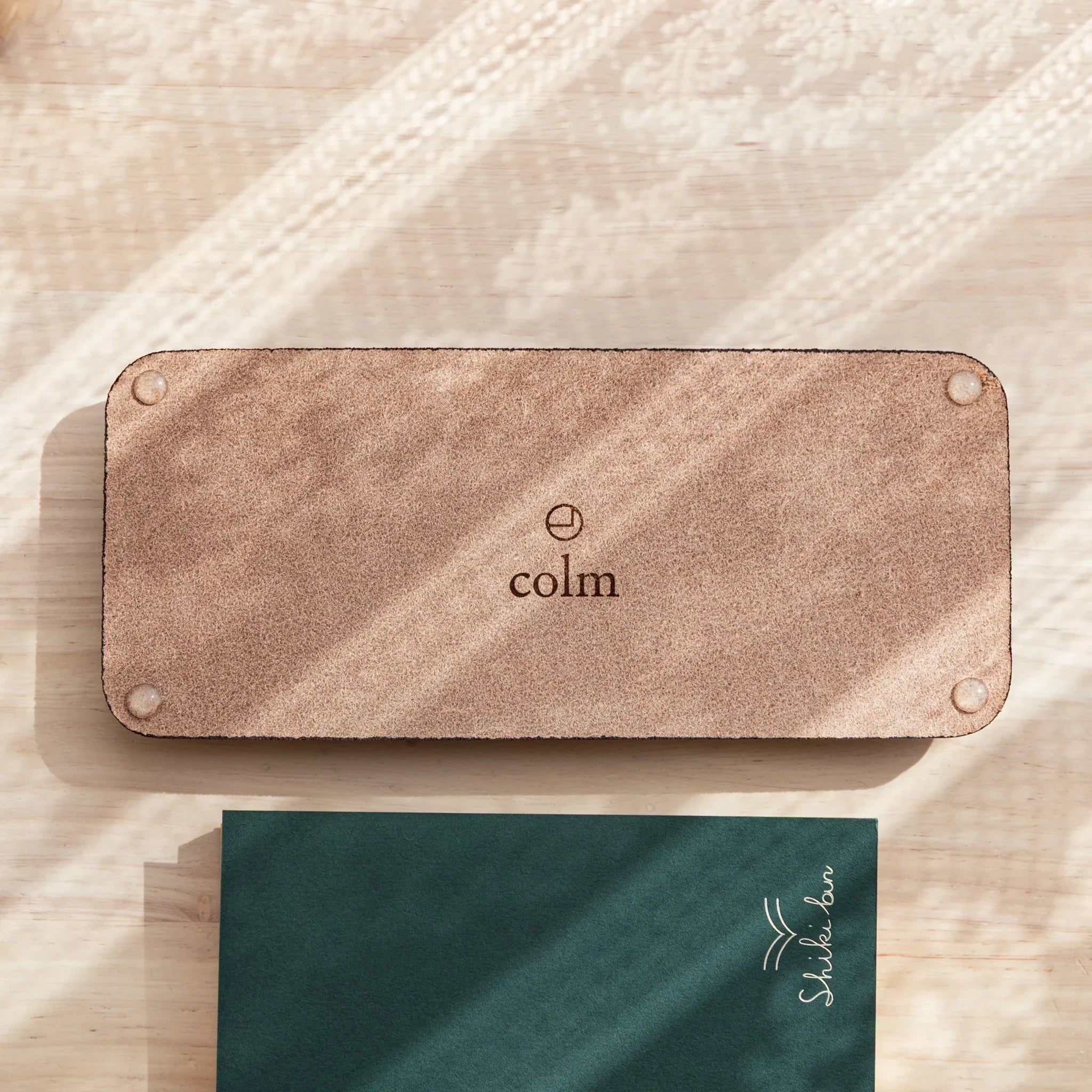 Burgundy colored suede pen tray back showing colm logo embossed on exterior backing of the pen tray clearly
