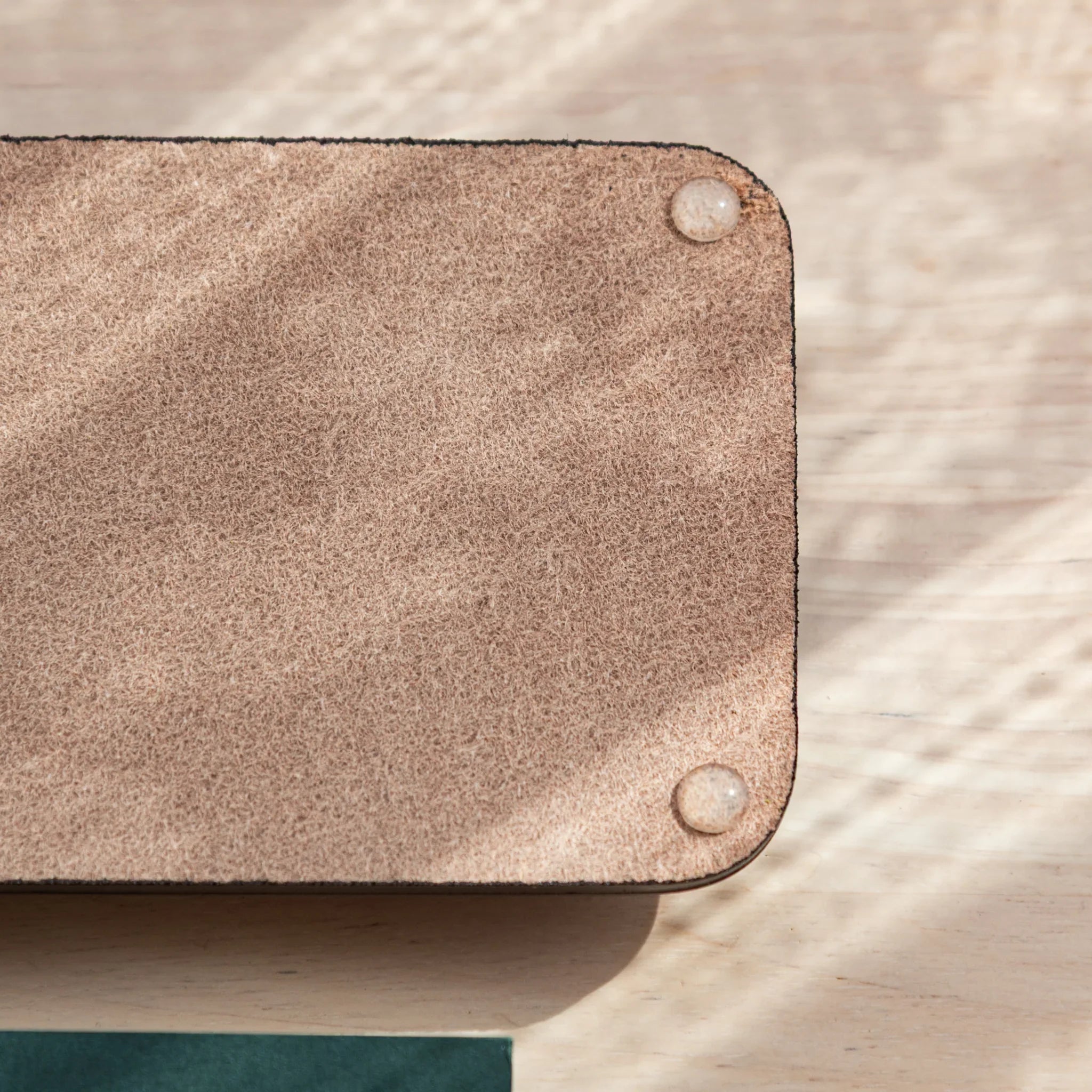 Burgundy suede corner detail of pen tray with snap button hardware visible and clearly shown in light