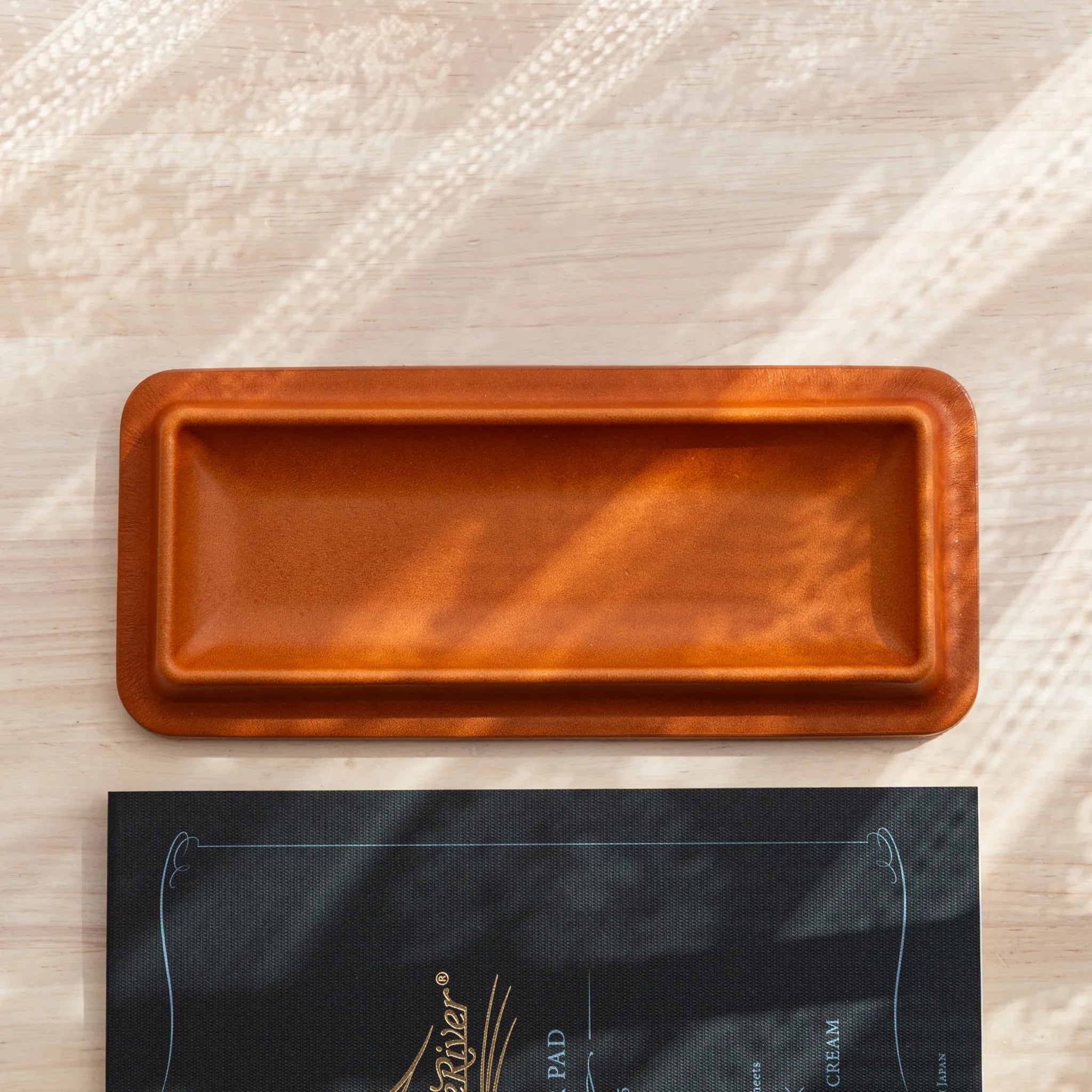 Empty cognac leather pen tray displayed from directly above with tan Tomoe River writing pad underneath