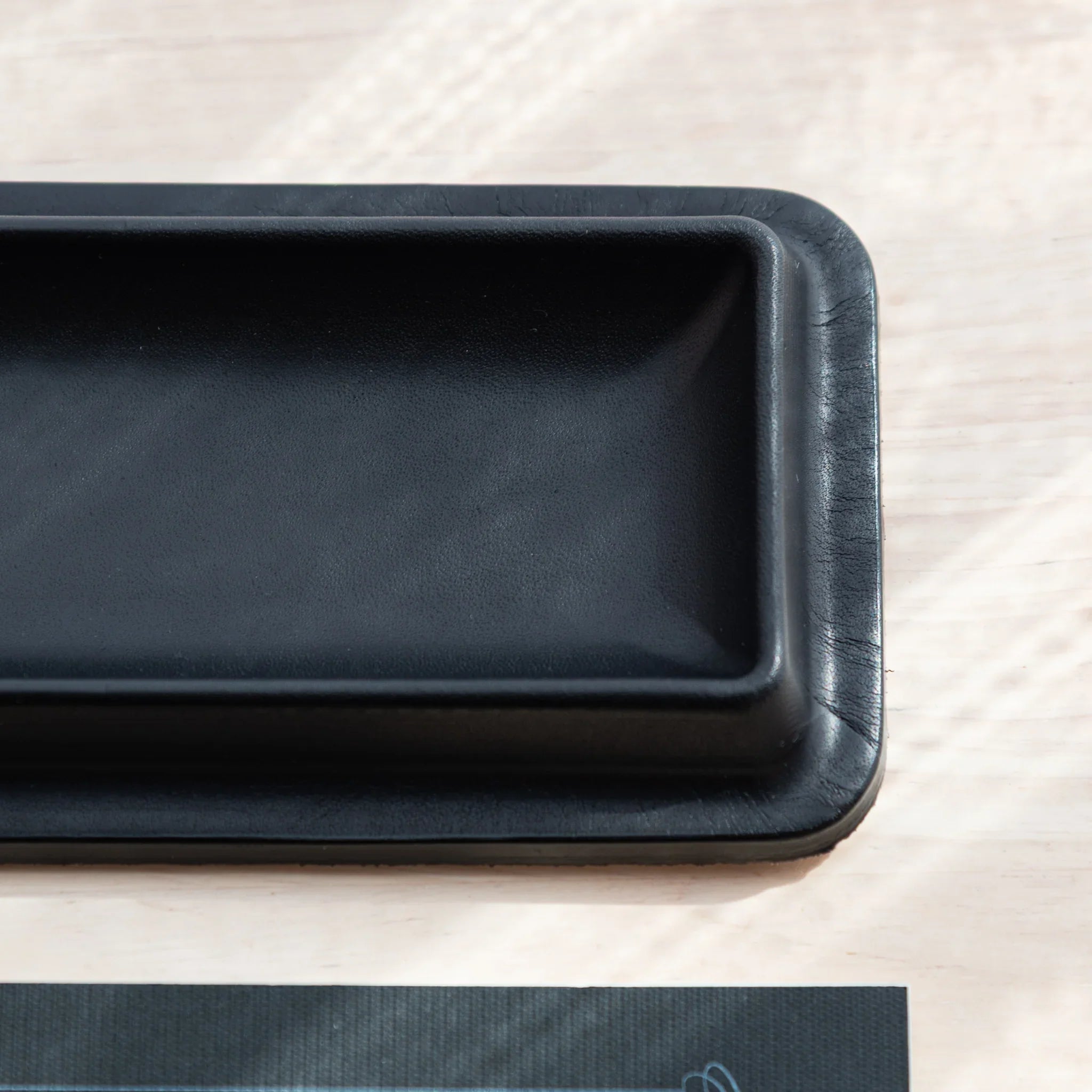 Black leather pen tray angled view with red patterned decorative maki-e pen display inside holder shown