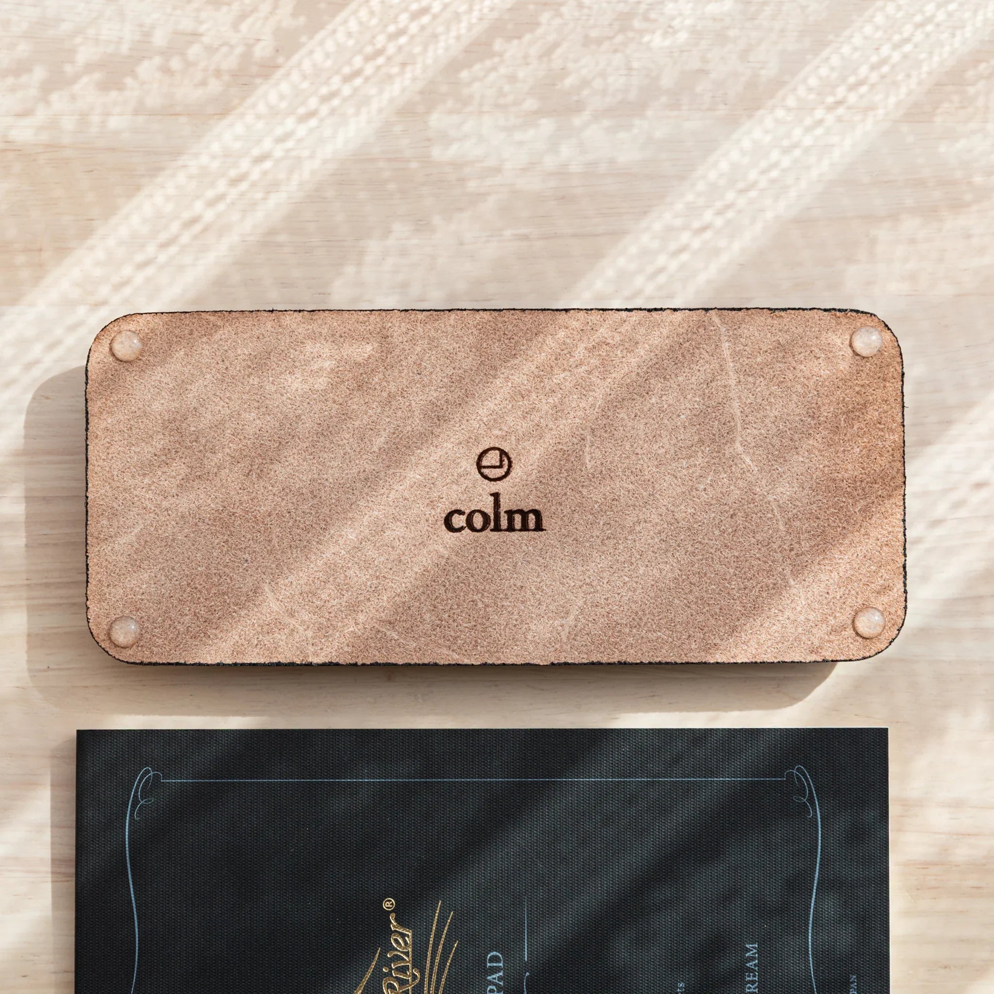 Black leather pen tray close-up with colm logo embossed on suede underside of the pen storage tray base
