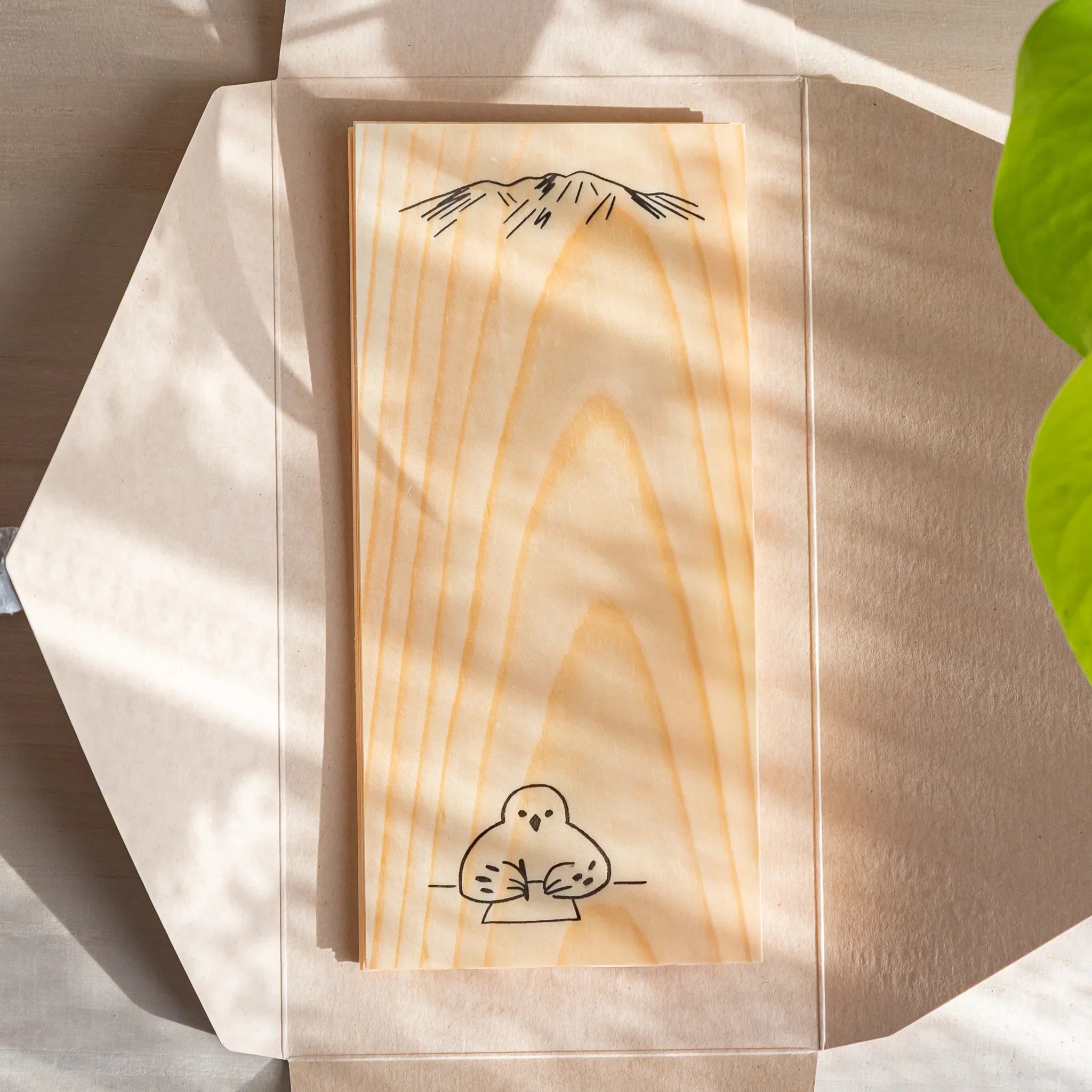 Japanese Stationery thin wood message card with bird illustration, placed in an open envelope on a light desk