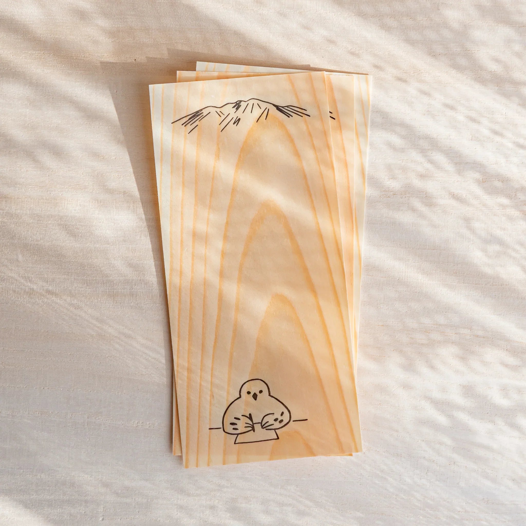 Japanese Stationery thin wood message cards stacked on a light desk, featuring natural pine grain and a bird illustration