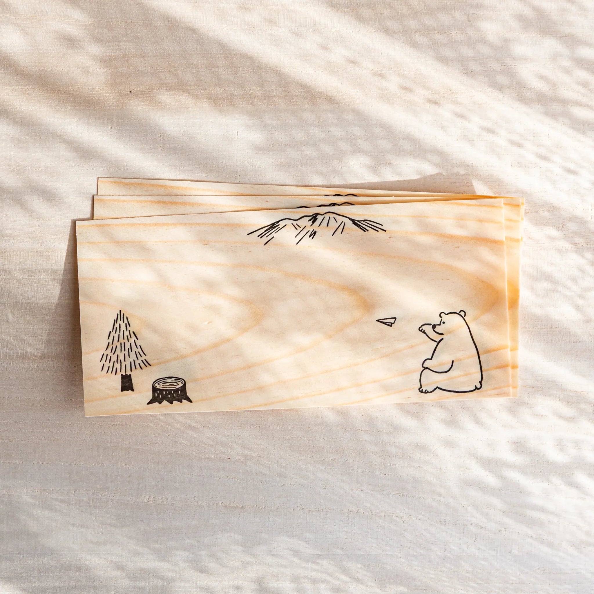 Japanese thin wood message cards stacked on desk with natural pine grain texture and bear and tree art designs
