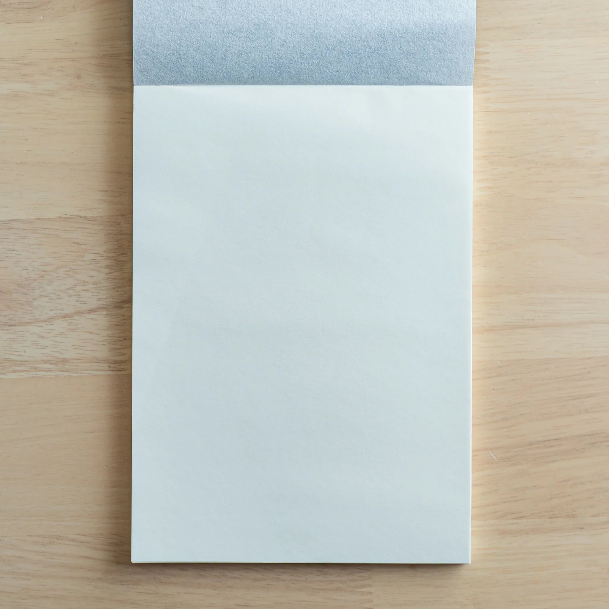 Facing blank pages in open position with gray fabric element at top, showcasing paper brightness and minimal texture