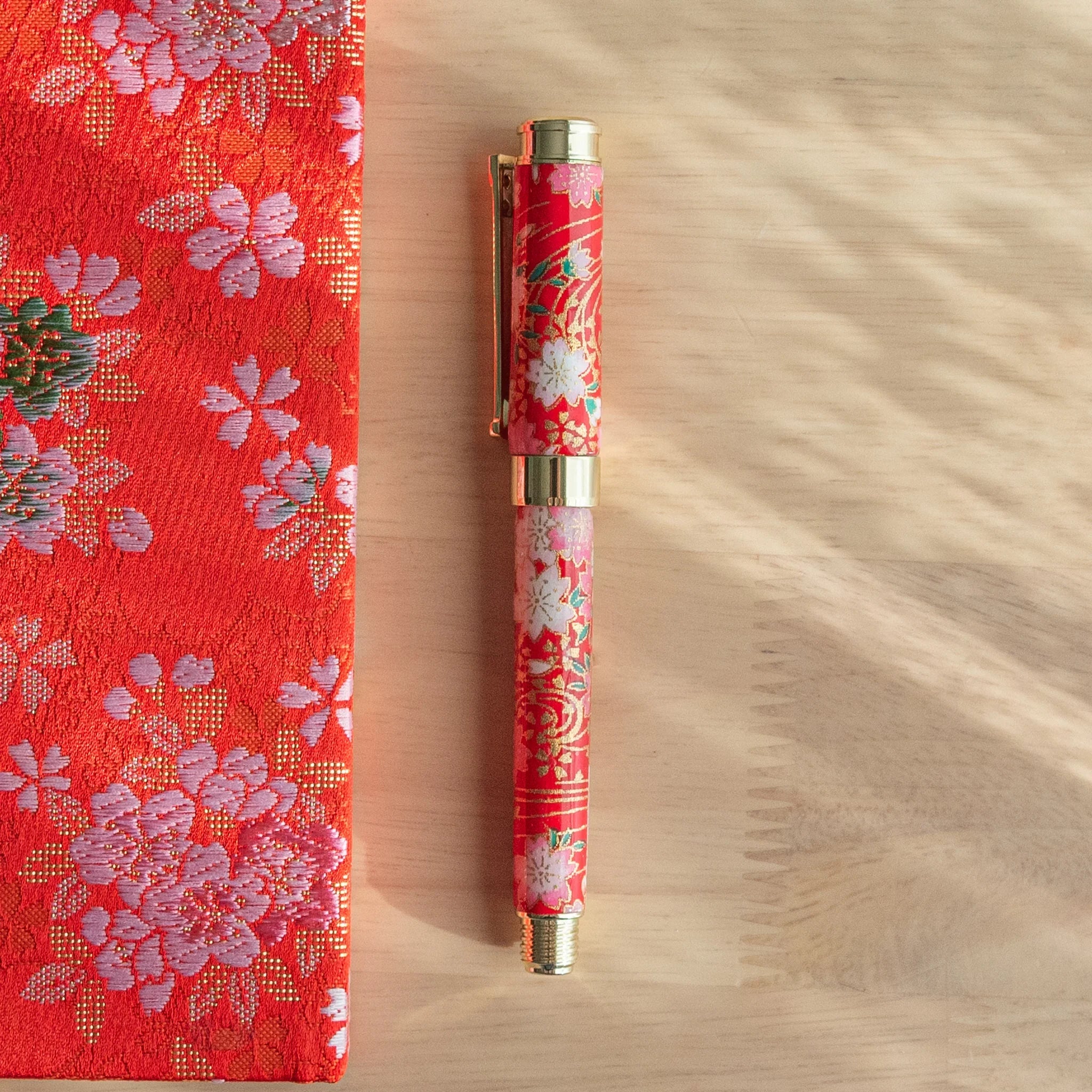 Japanese fountain pen with red Mino washi featuring white and pink cherry blossoms and gold decoration with nib