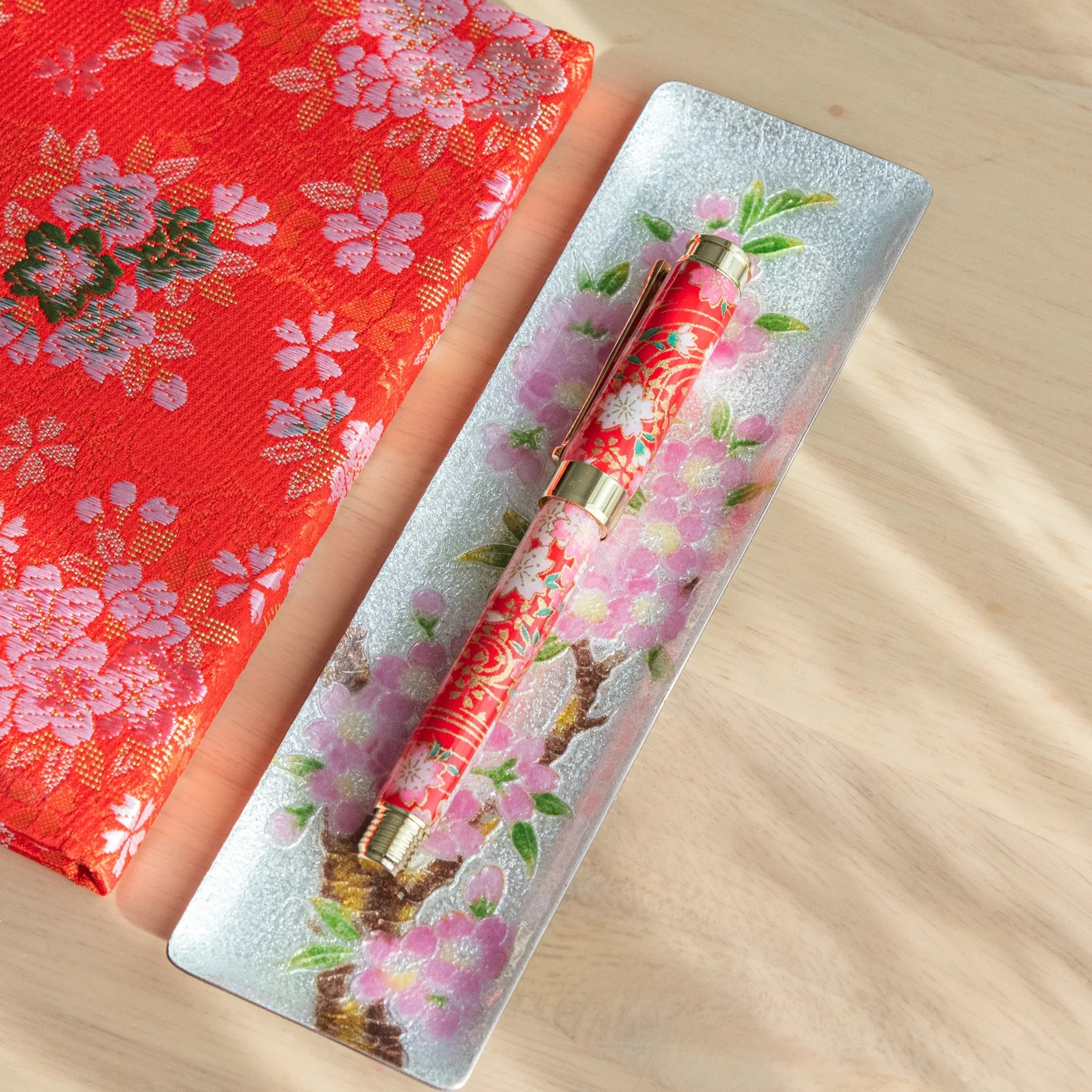 Weeping Sakura Mino Washi fountain pen positioned on red washi paper with white drooping floral pattern with nib