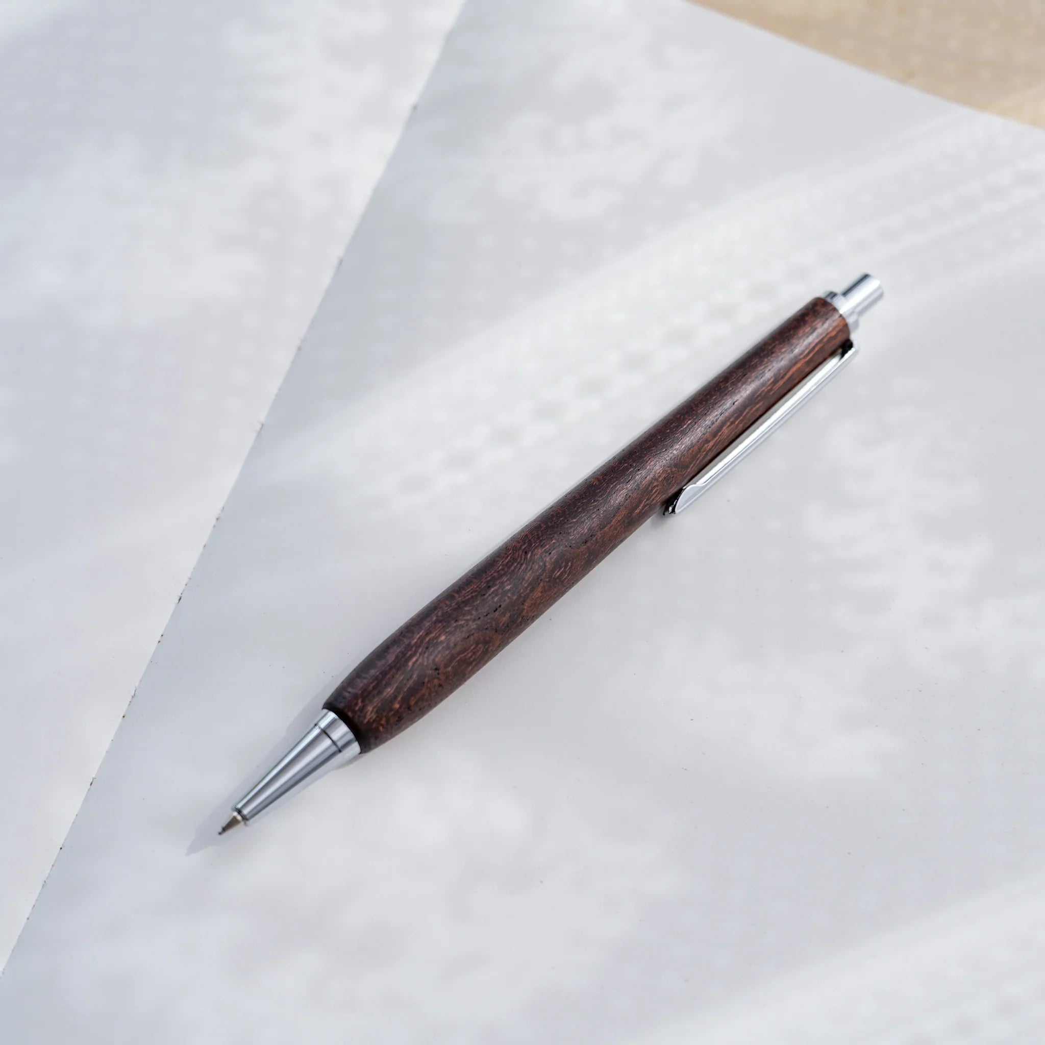 Zelkova wood urushi lacquered mechanical pencil in dark reddish-brown on white paper, Japanese keyaki wood