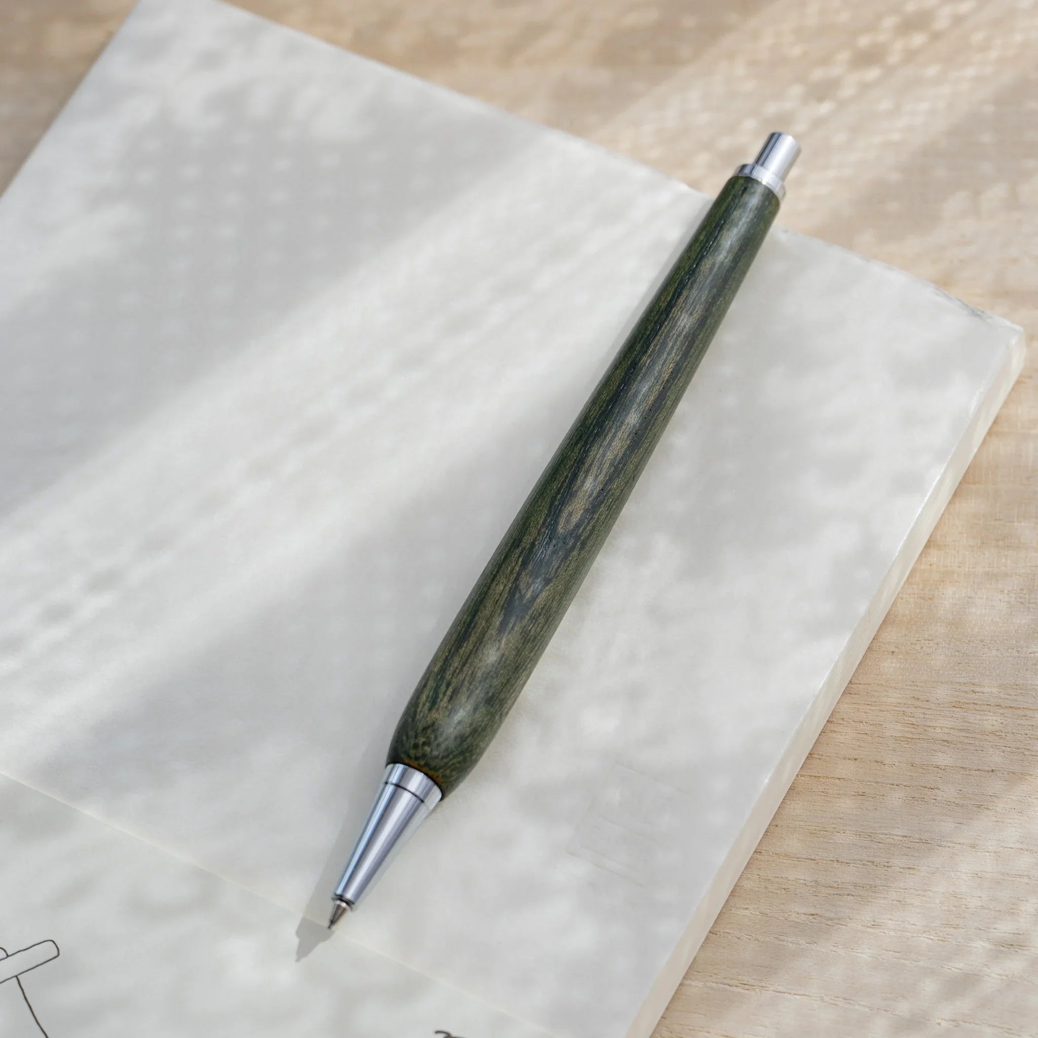 Olive green zelkova wood urushi mechanical pencil, close-up of knock end and silver clip, Japanese keyaki wood