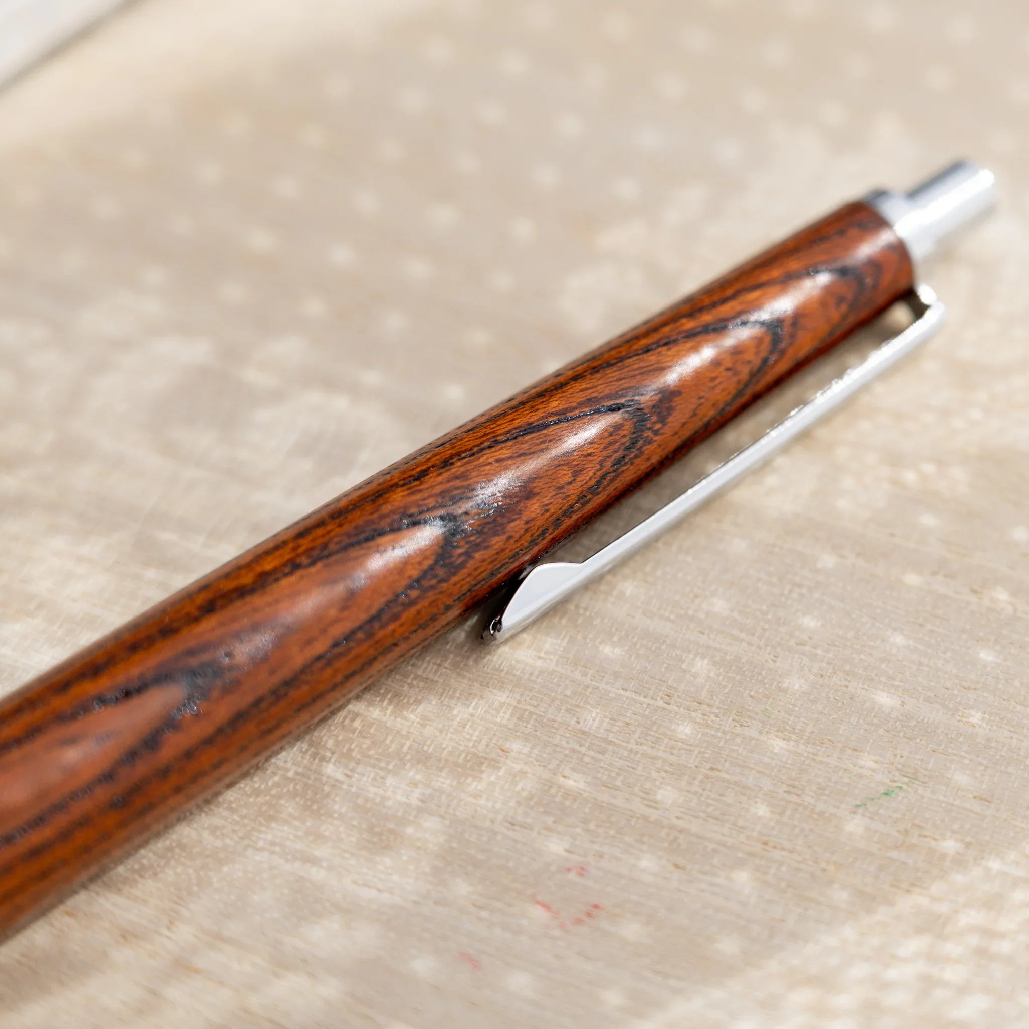 Amber-brown zelkova wood urushi mechanical pencil, close-up of barrel wood grain and silver clip, Japanese keyaki