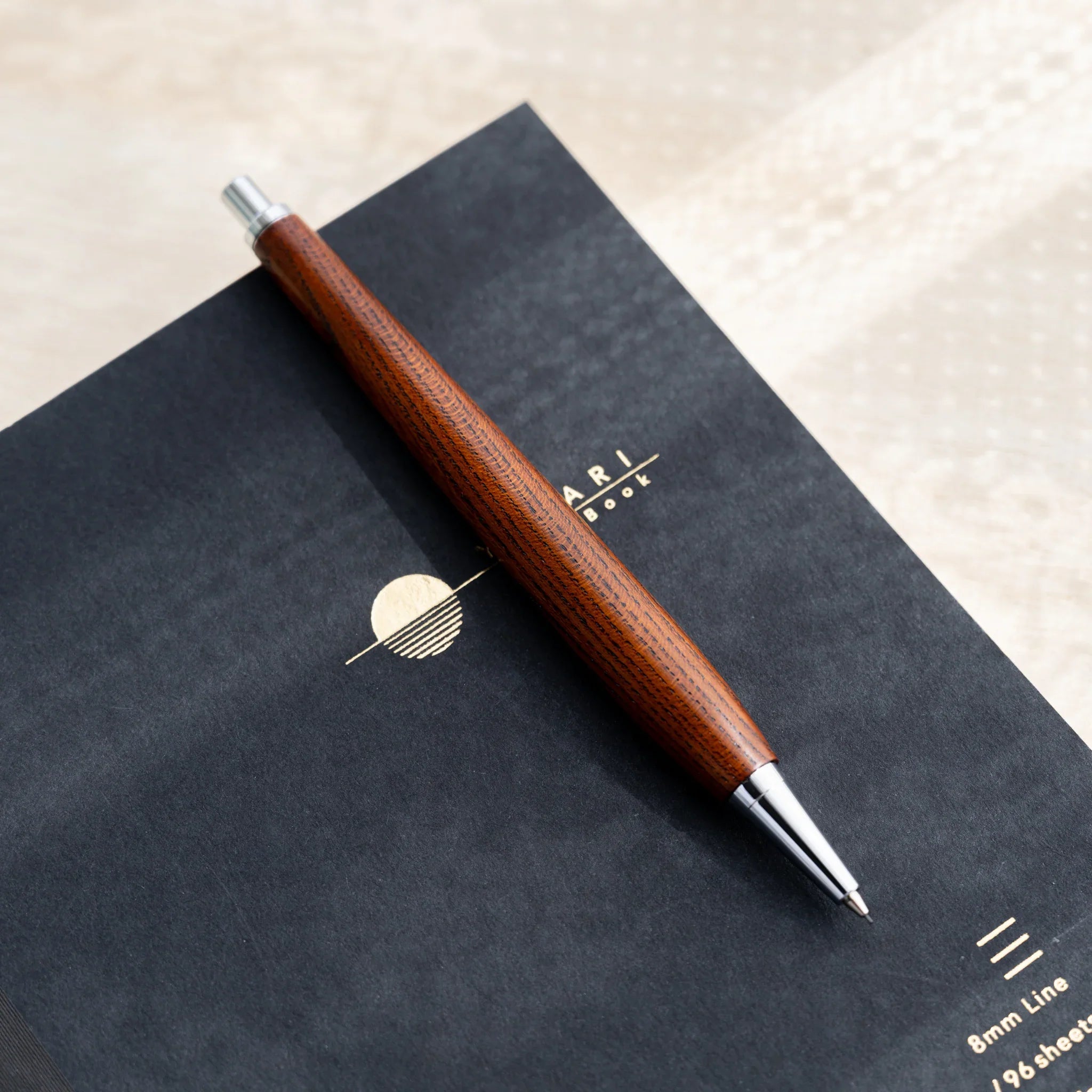 Amber-brown zelkova wood urushi mechanical pencil, close-up of knock button and silver clip, Japanese keyaki wood