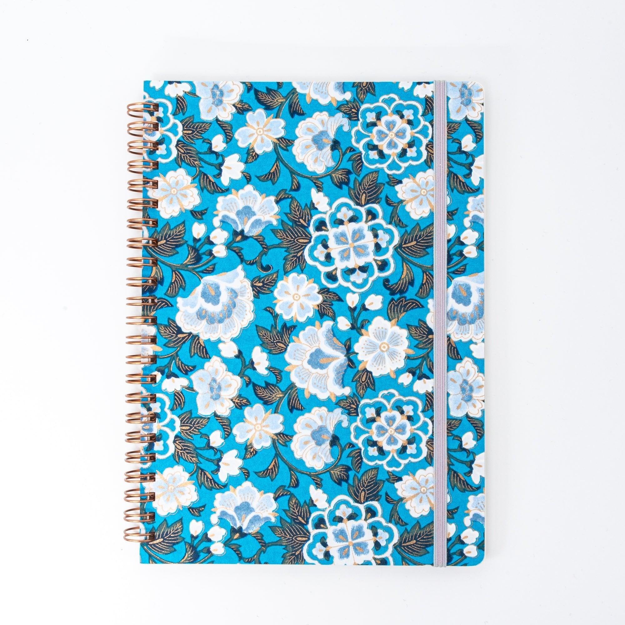 Hand-dyed blue garden washi notebook opened showing spiral binding and blank pages for daily note-taking