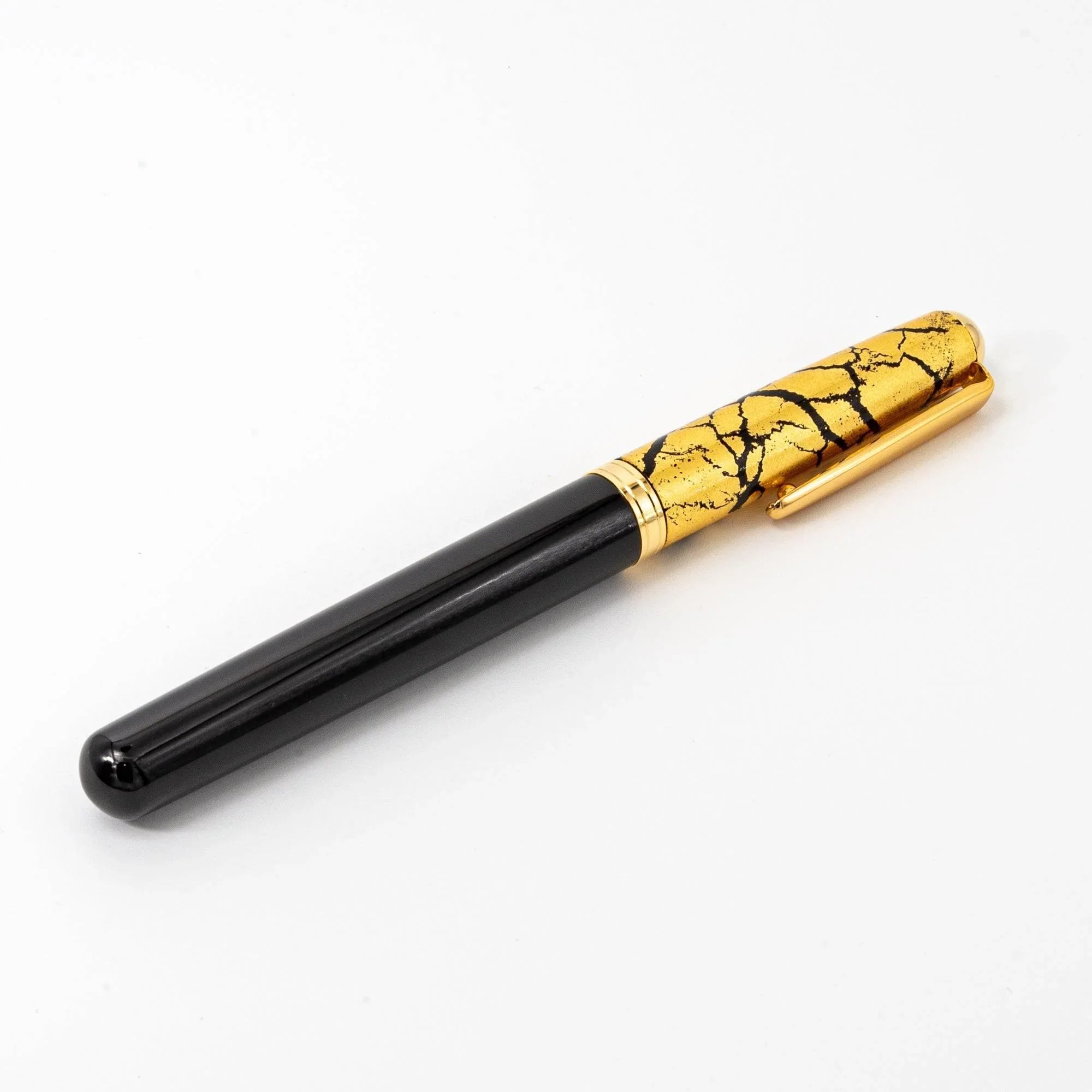 Black fountain pen with open nib displaying intricate gold crackle pattern on dark lacquer barrel detail