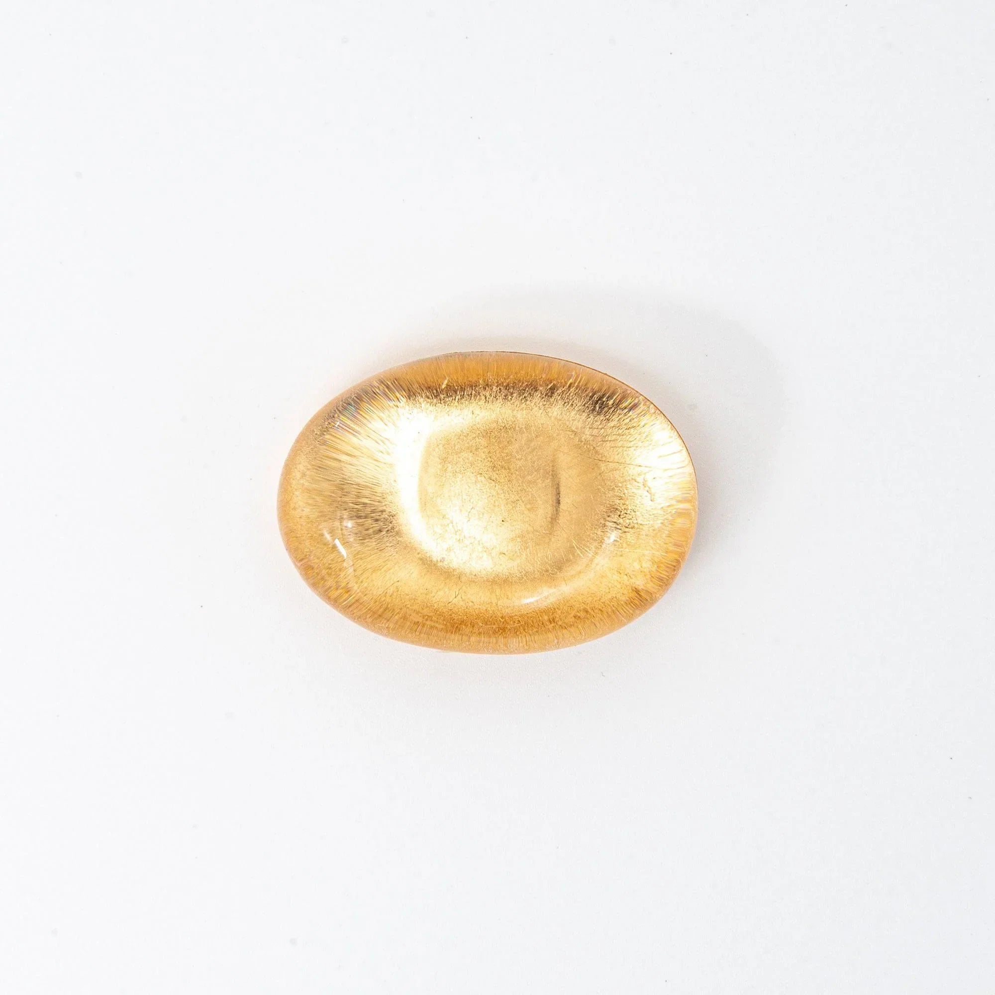 Japanese translucent amber glass pen rest with floating gold leaf elements suspended inside, overhead viewing display