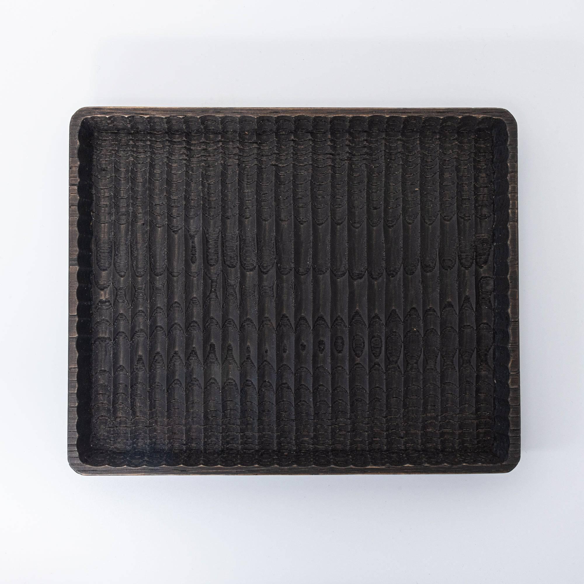 Wide chestnut pen tray displaying carved wave-like channels in light natural wood with pens with clear visibility of design