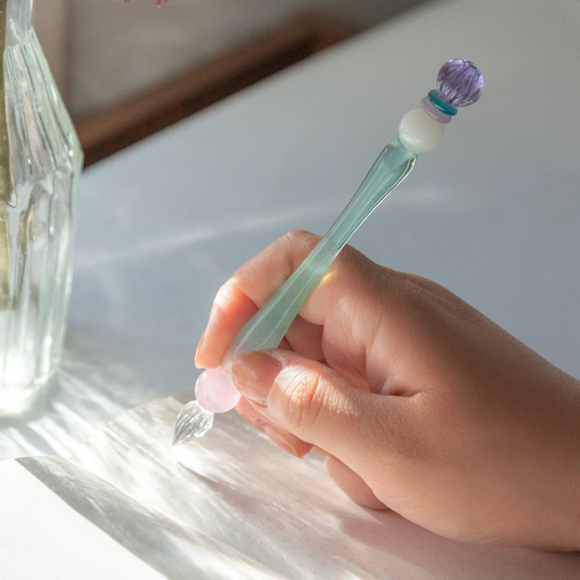 King's Scepter Candy glass dip pen held in hand showing writing grip with purple and gold bead ornament