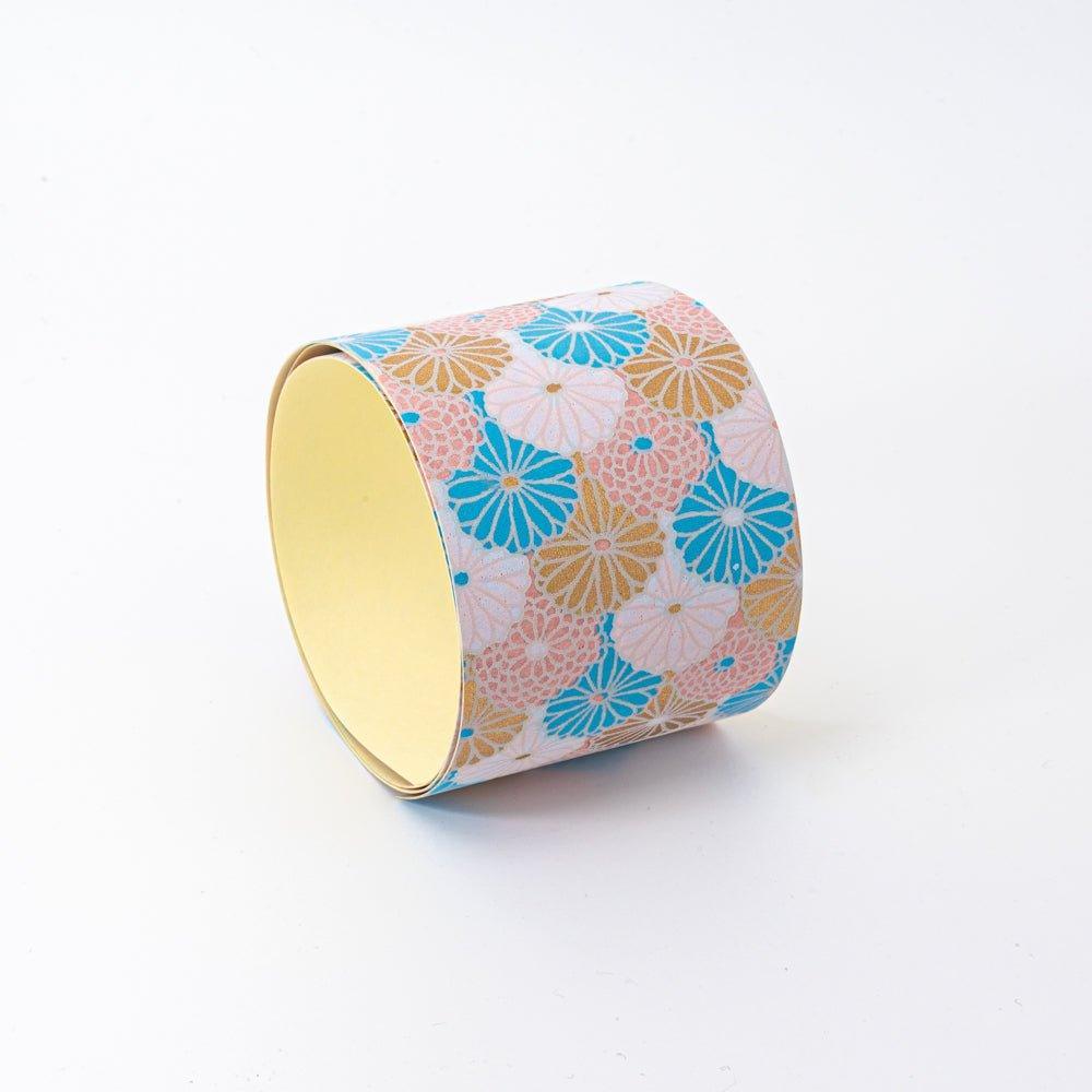 Sky Blossom yuzen washi tape roll standing upright showing yellow interior and pastel chrysanthemum pattern on exterior