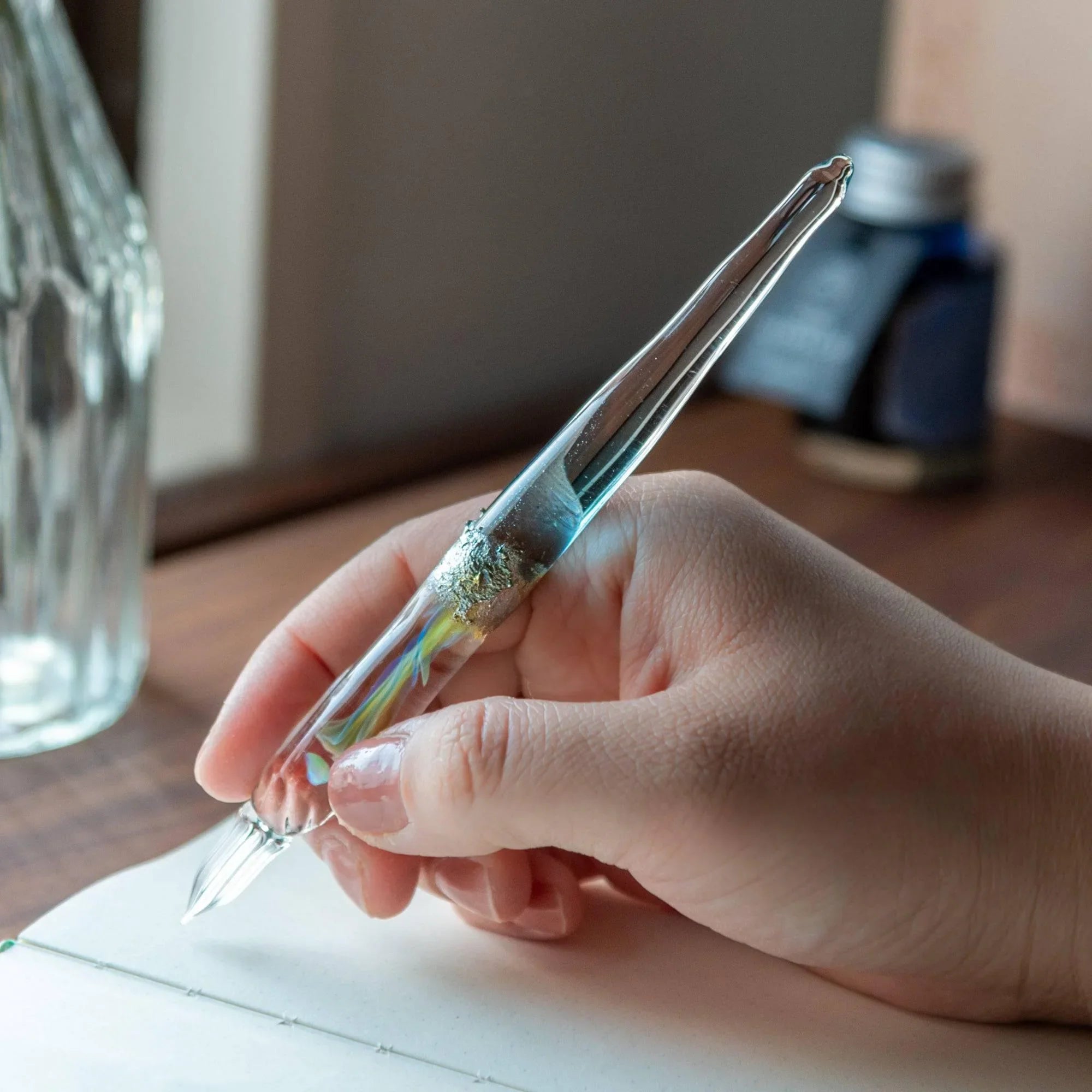Overhead angle of light blue glass dip pen showing twisted nib detail reflecting moon goddess inspiration shine